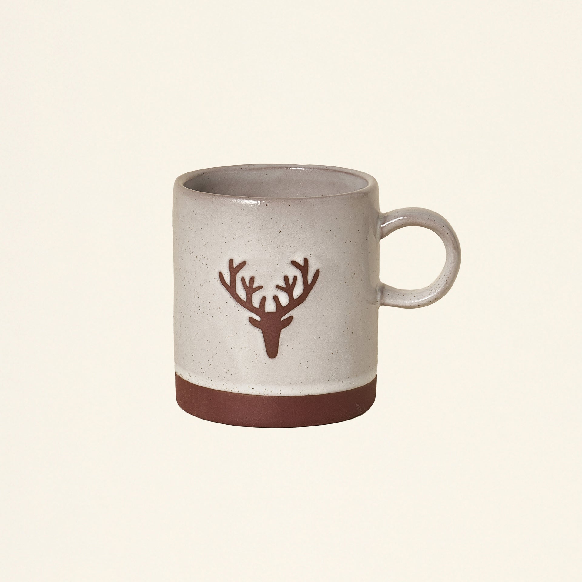 A cream-colored stoneware mug with a deer head outline.