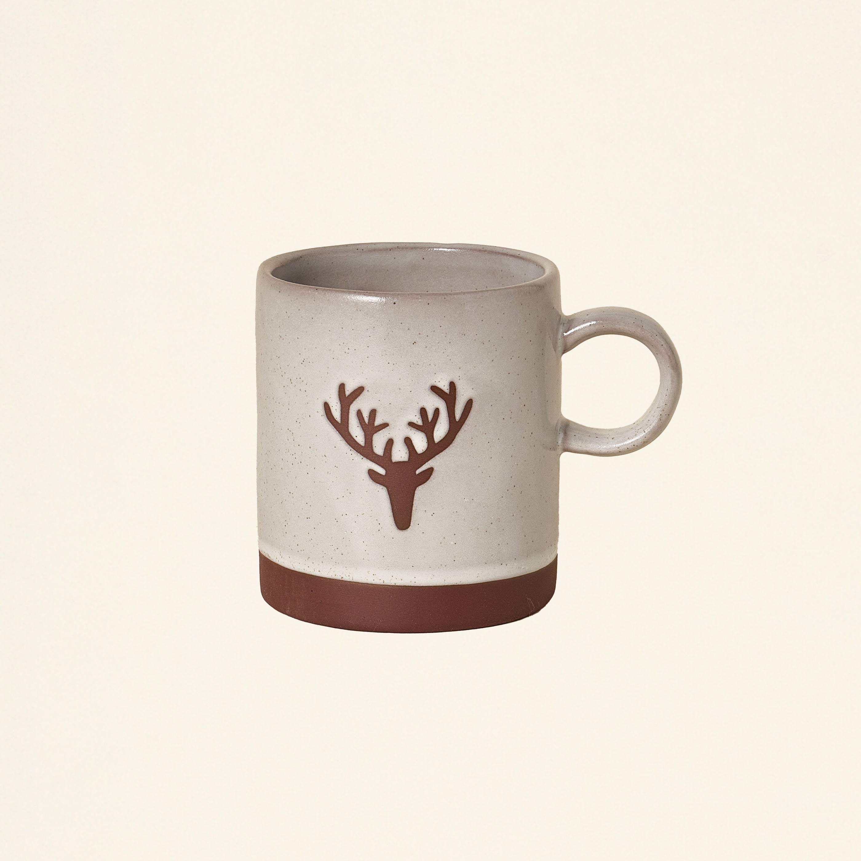 A cream-colored stoneware mug with a deer head outline.