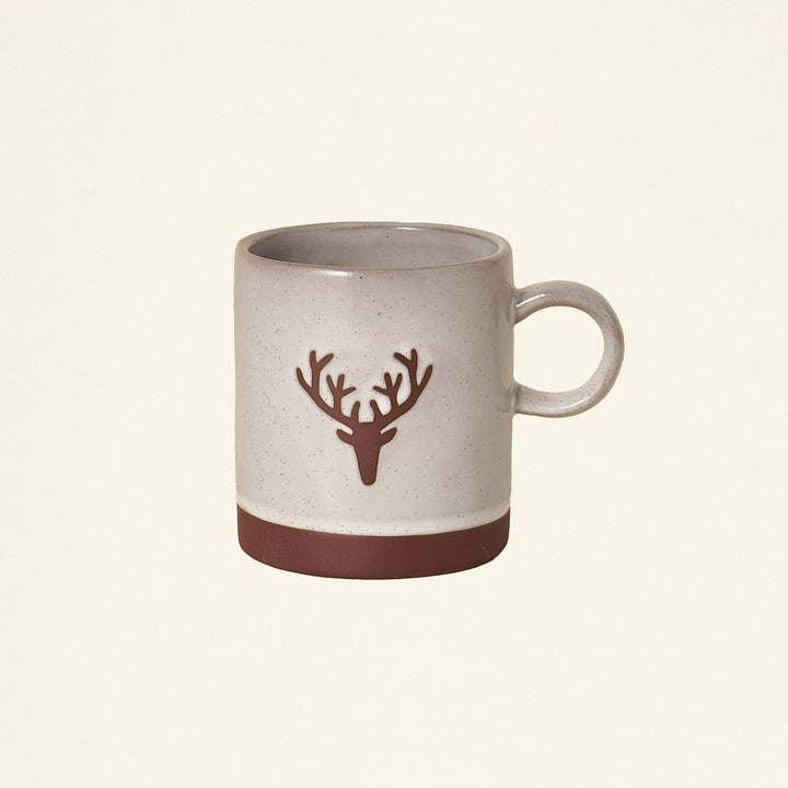 A cream-colored stoneware mug with a deer head outline.