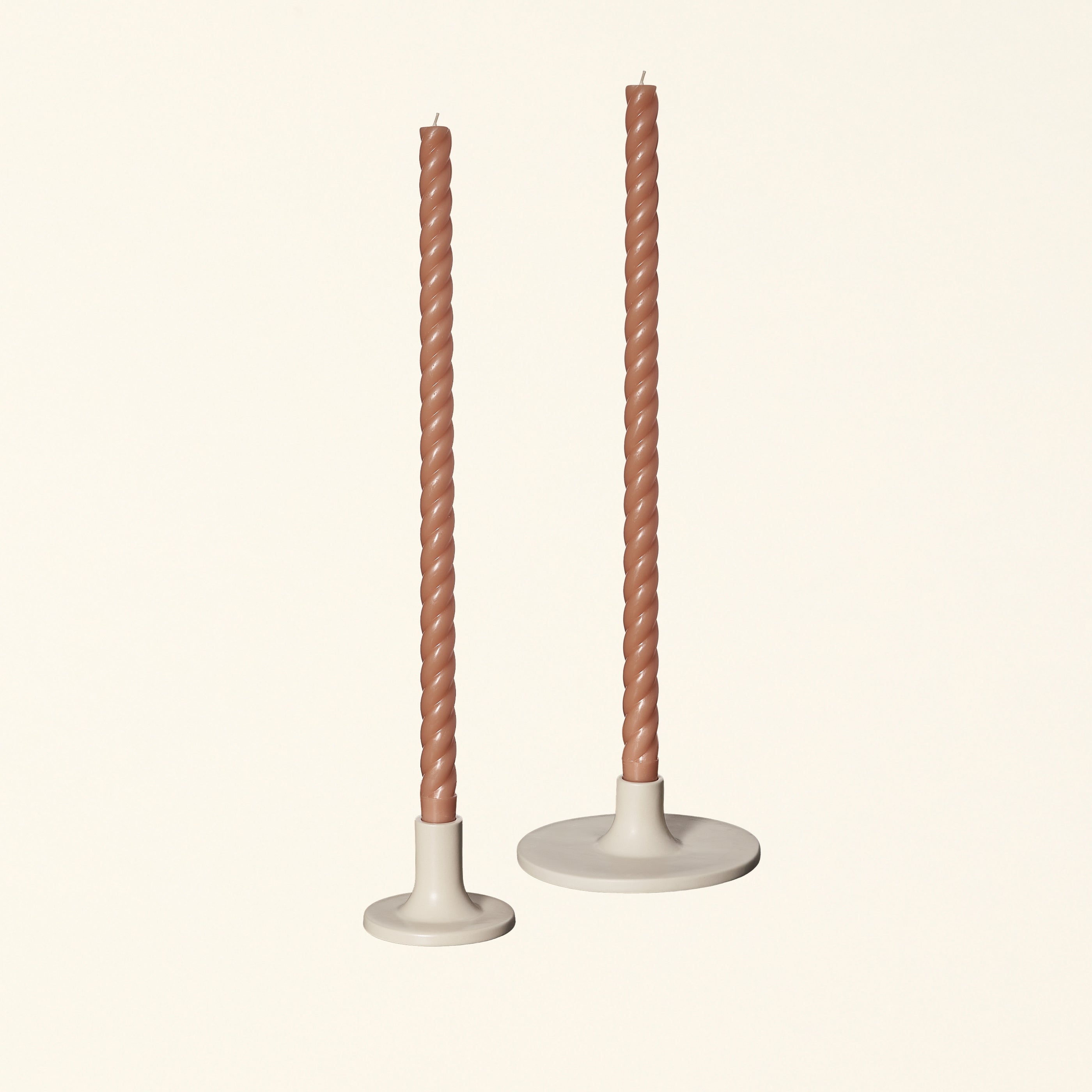Set of two beige ceramic taper candle holders with candles.