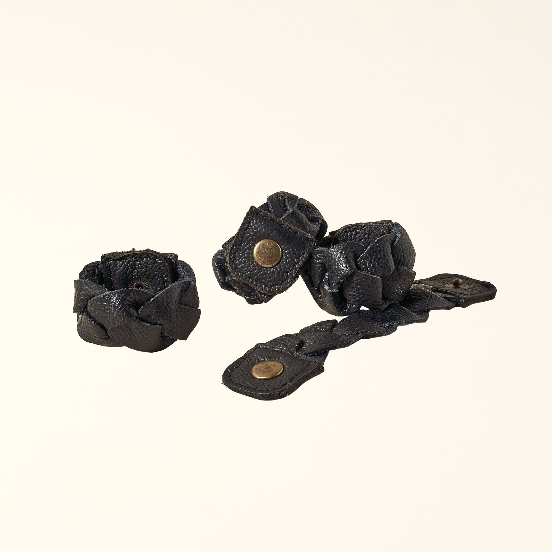 Set of four black braided leather napkin rings with a snap closure.