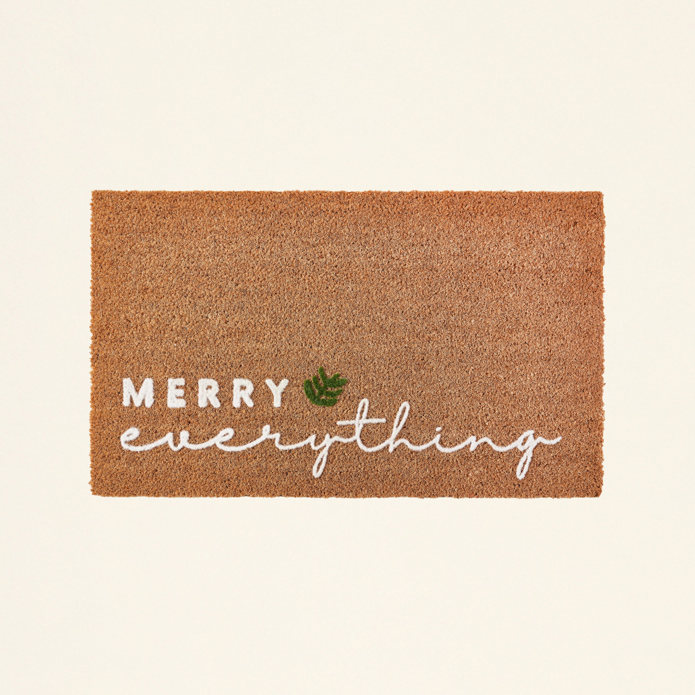 A doormat with a raised "Merry Everything" text and a leaf motif.