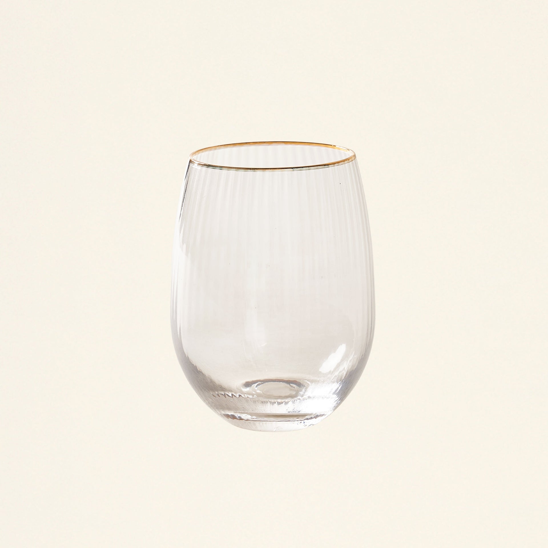 A stemless glass with a gold rim filled with wine or juice.