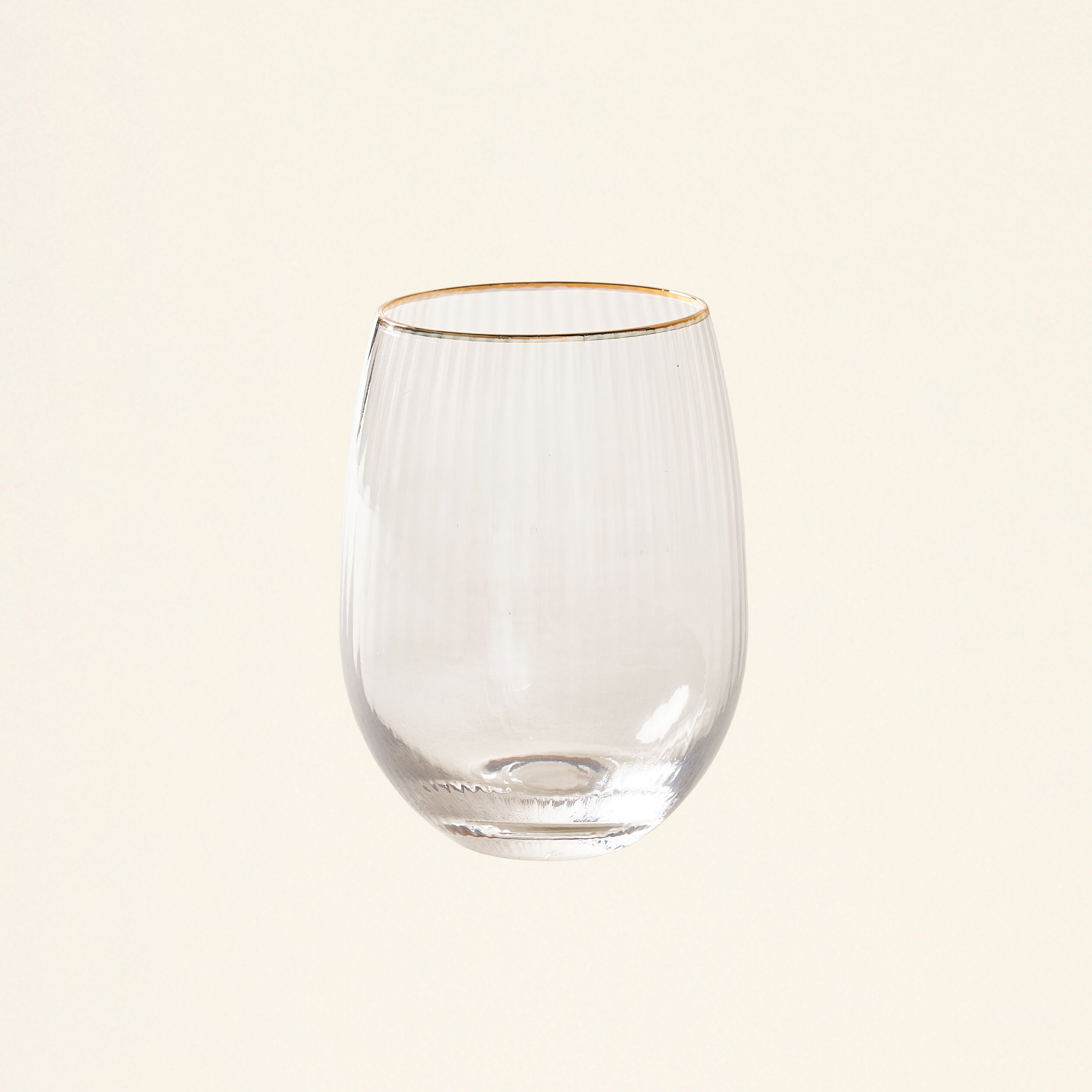 A stemless glass with a gold rim filled with wine or juice.