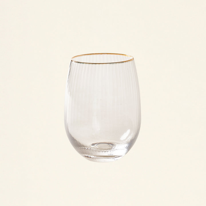 A stemless glass with a gold rim filled with wine or juice.