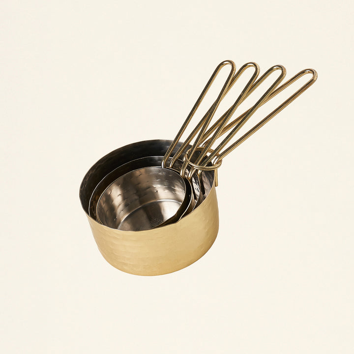 Set of four hammered gold measuring cups.