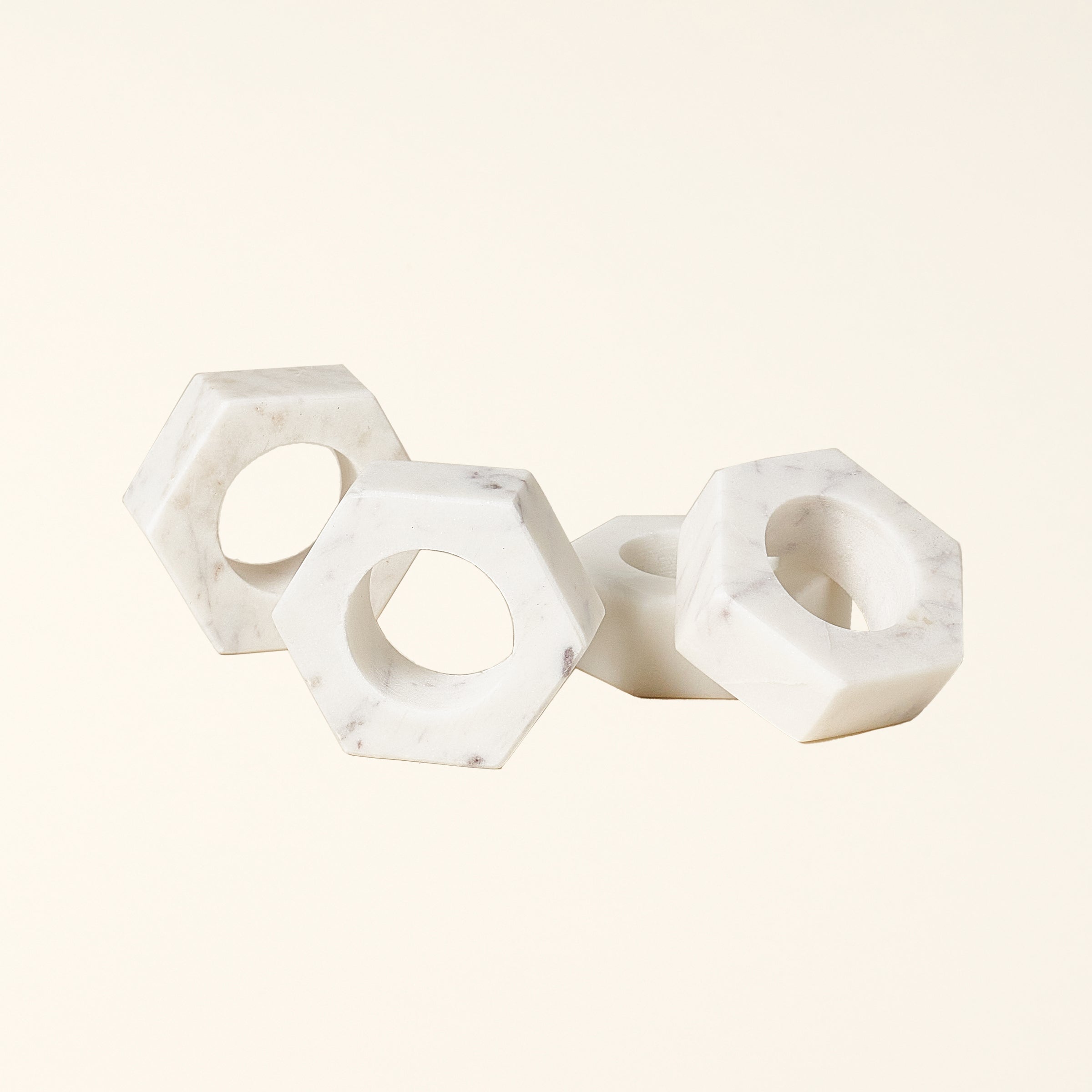 Set of four hand-crafted white marble napkin rings with a modern geometric design.