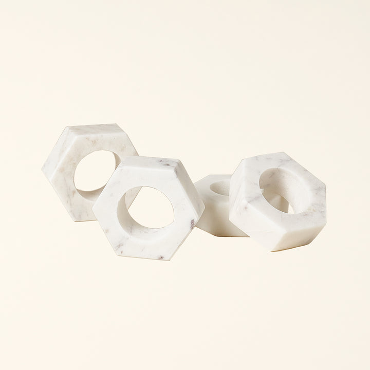 Set of four hand-crafted white marble napkin rings with a modern geometric design.