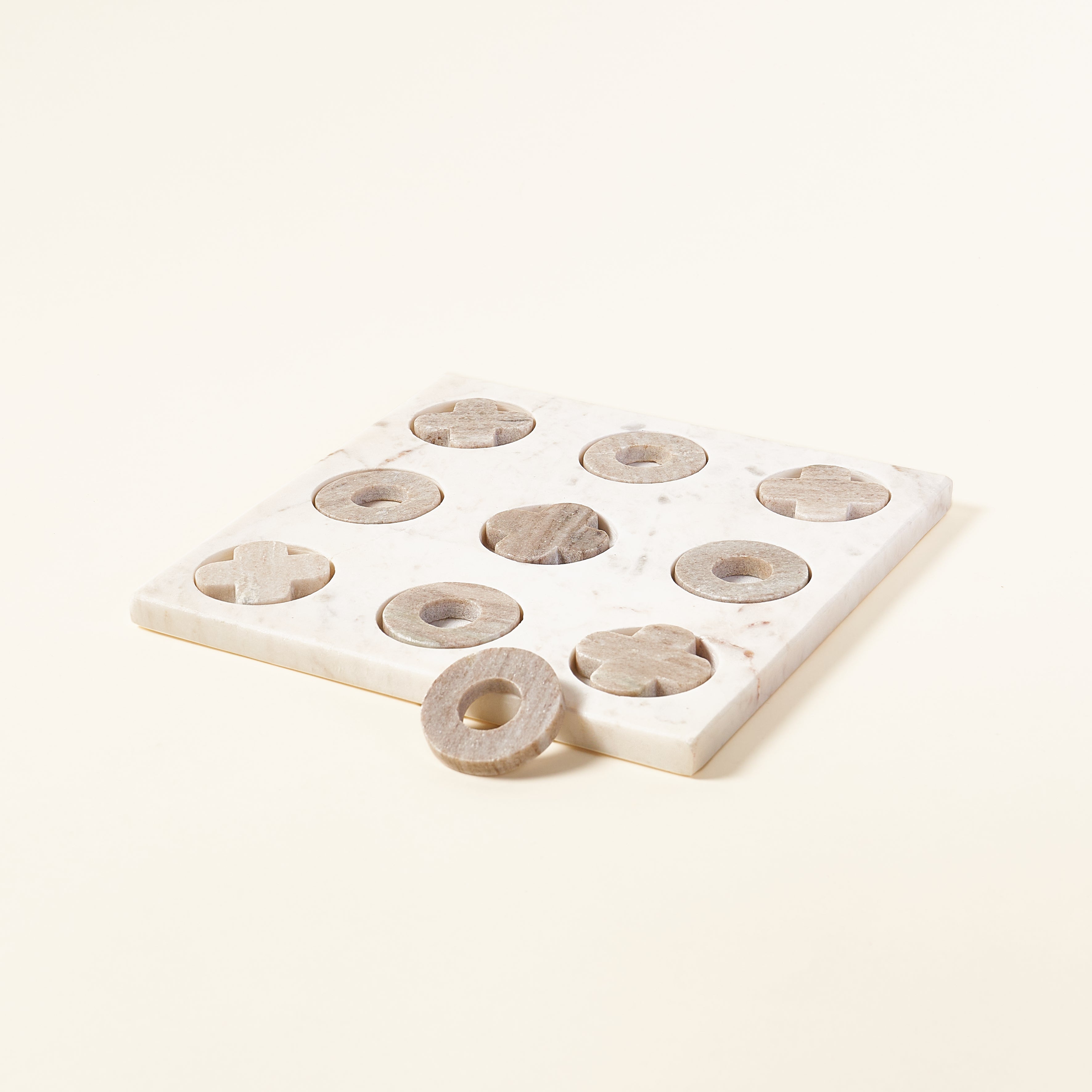 White marble tic-tac-toe game board with grey marble pieces.