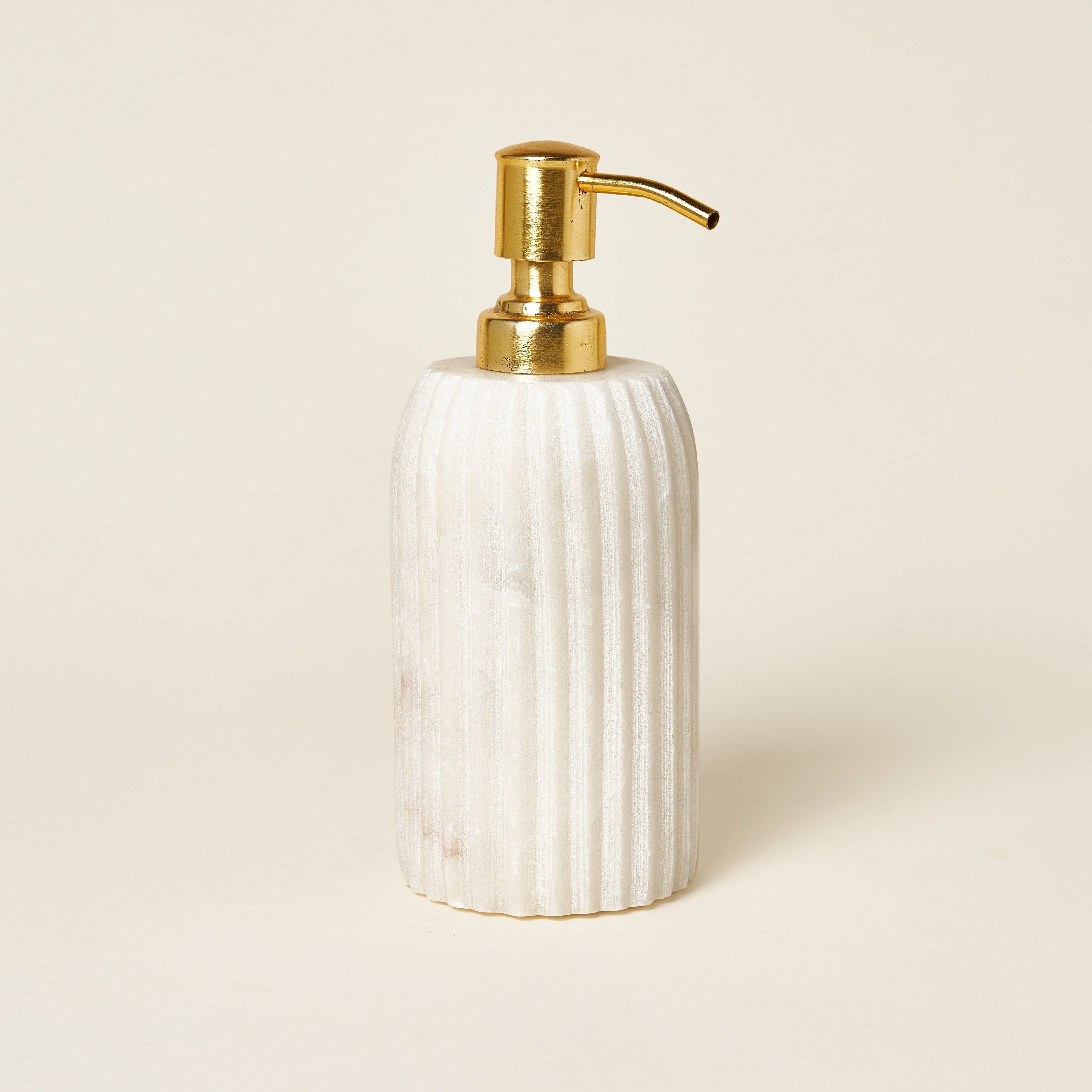 White marble fluted soap dispenser with a brass pump.