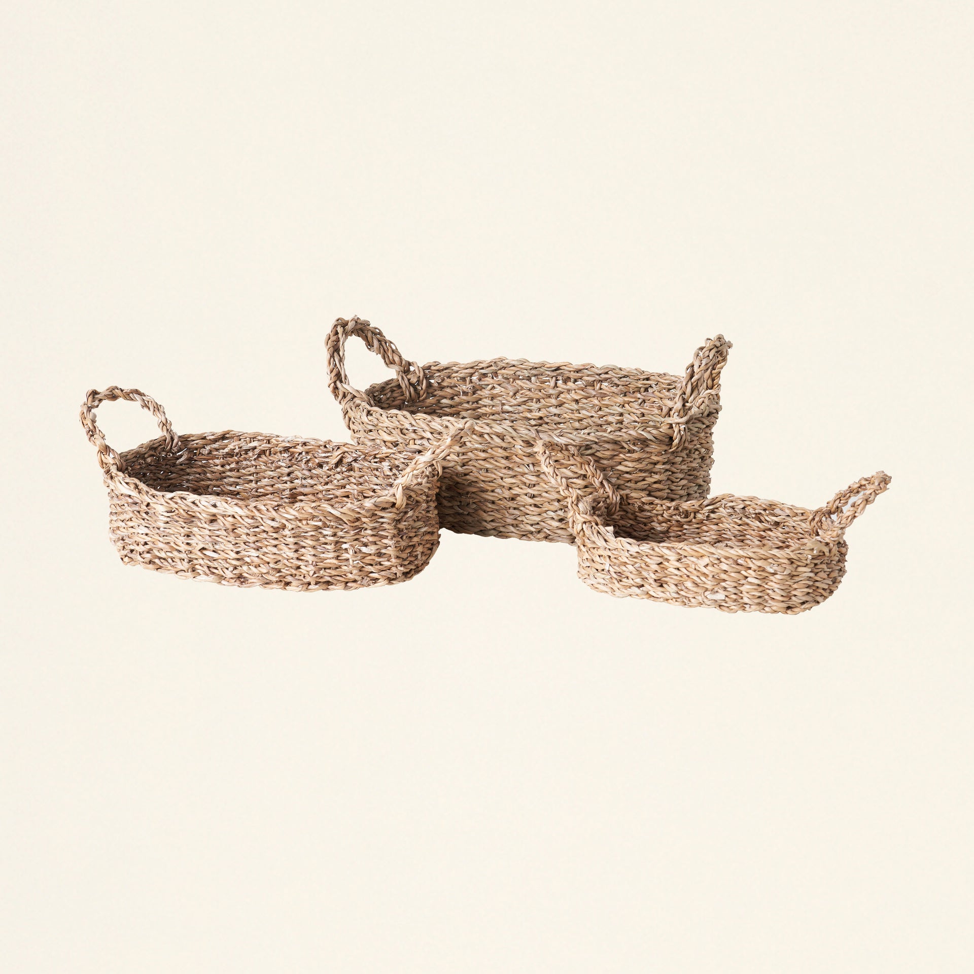 Set of three oval seagrass baskets with handles.