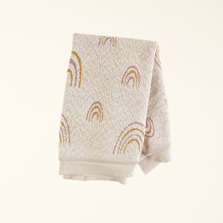 A soft, knit baby blanket with a neutral-colored rainbow pattern.