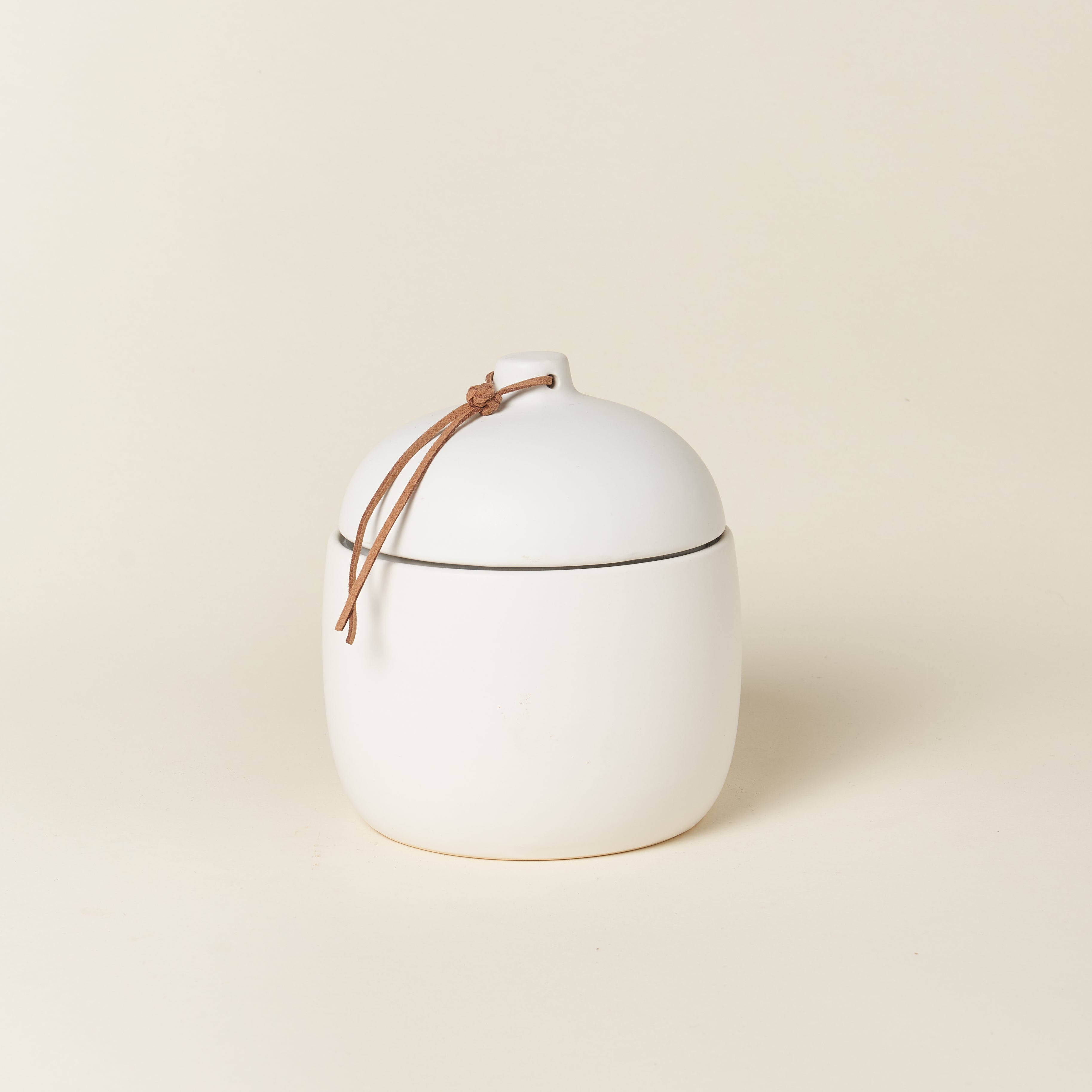 Ceramic jar with a lid and a leather strap.
