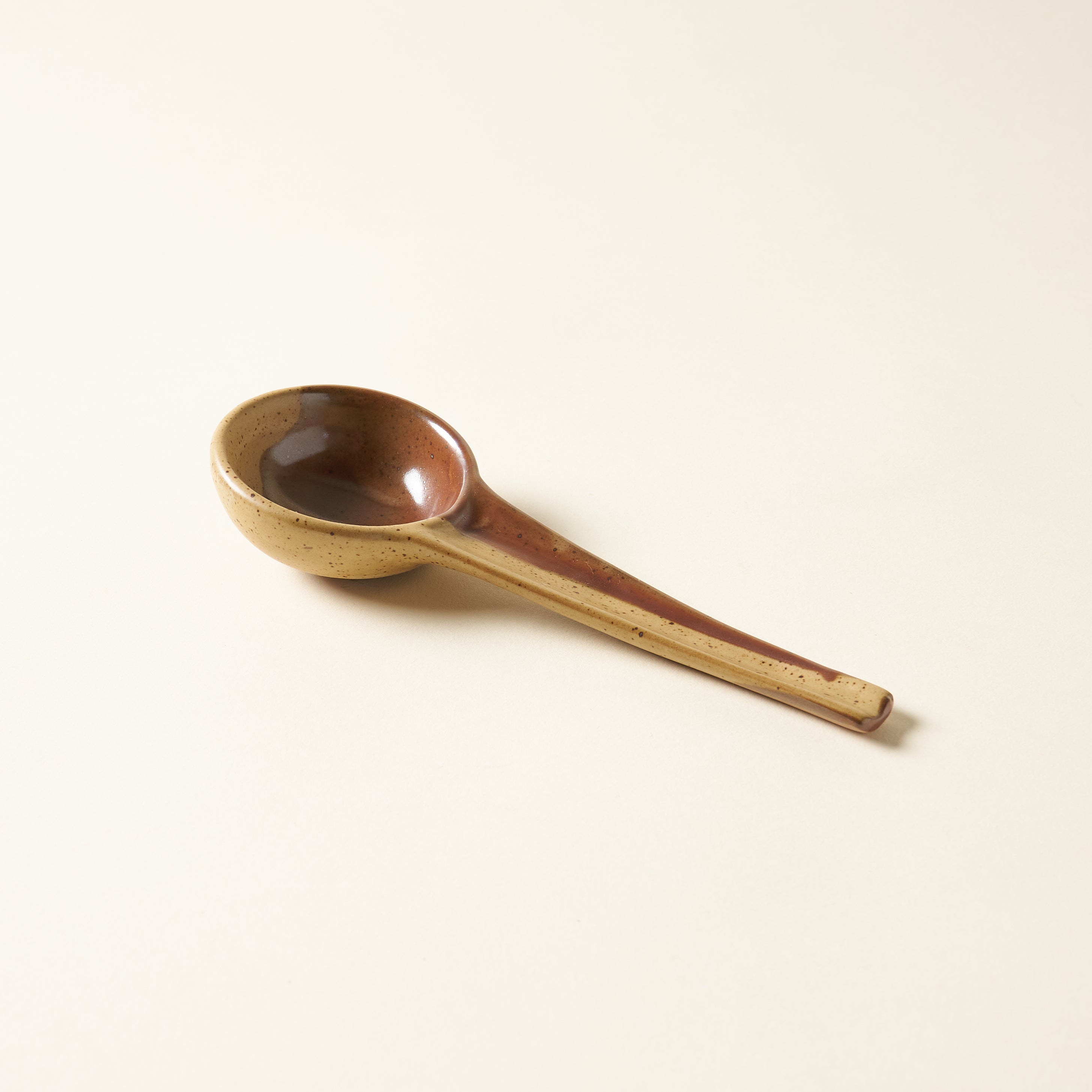 A two-tone stoneware spoon with a brown and black reactive glaze.