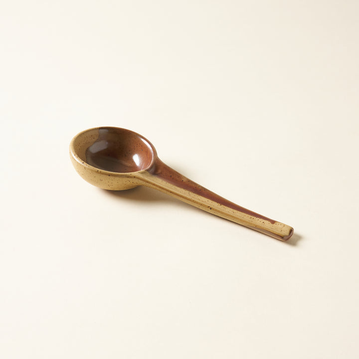 A two-tone stoneware spoon with a brown and black reactive glaze.