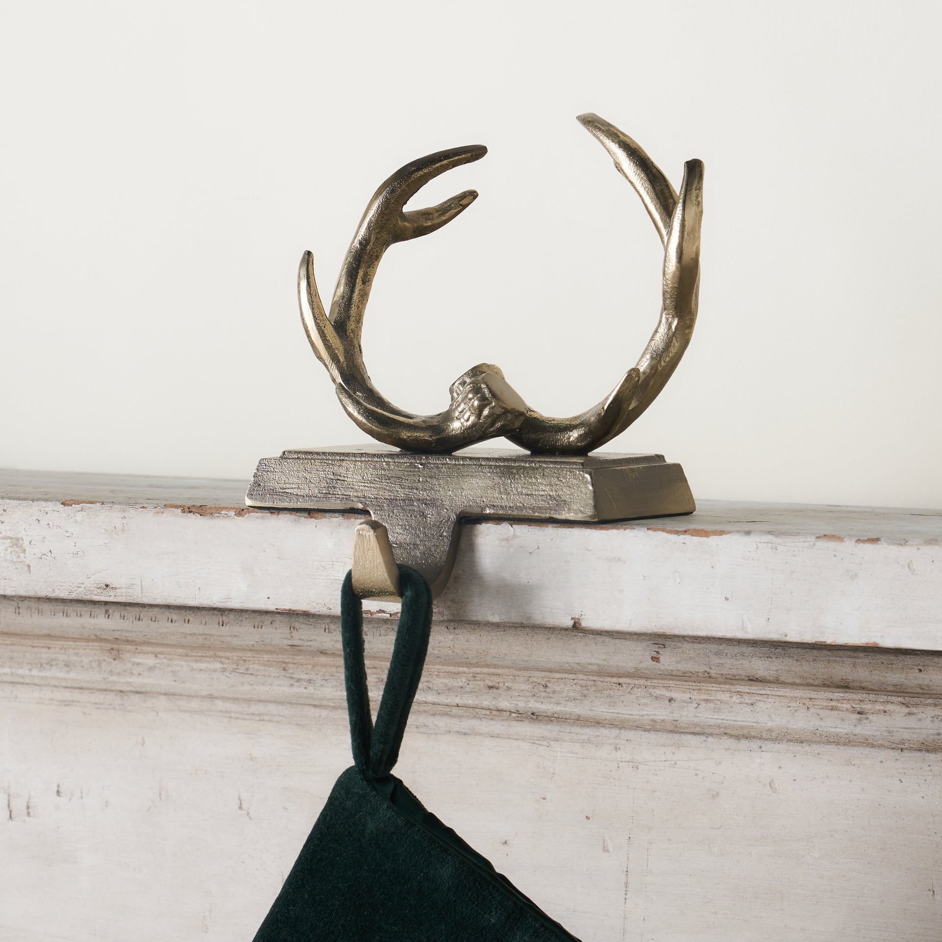 A decorative stocking holder with an antler design and an aged gold finish.