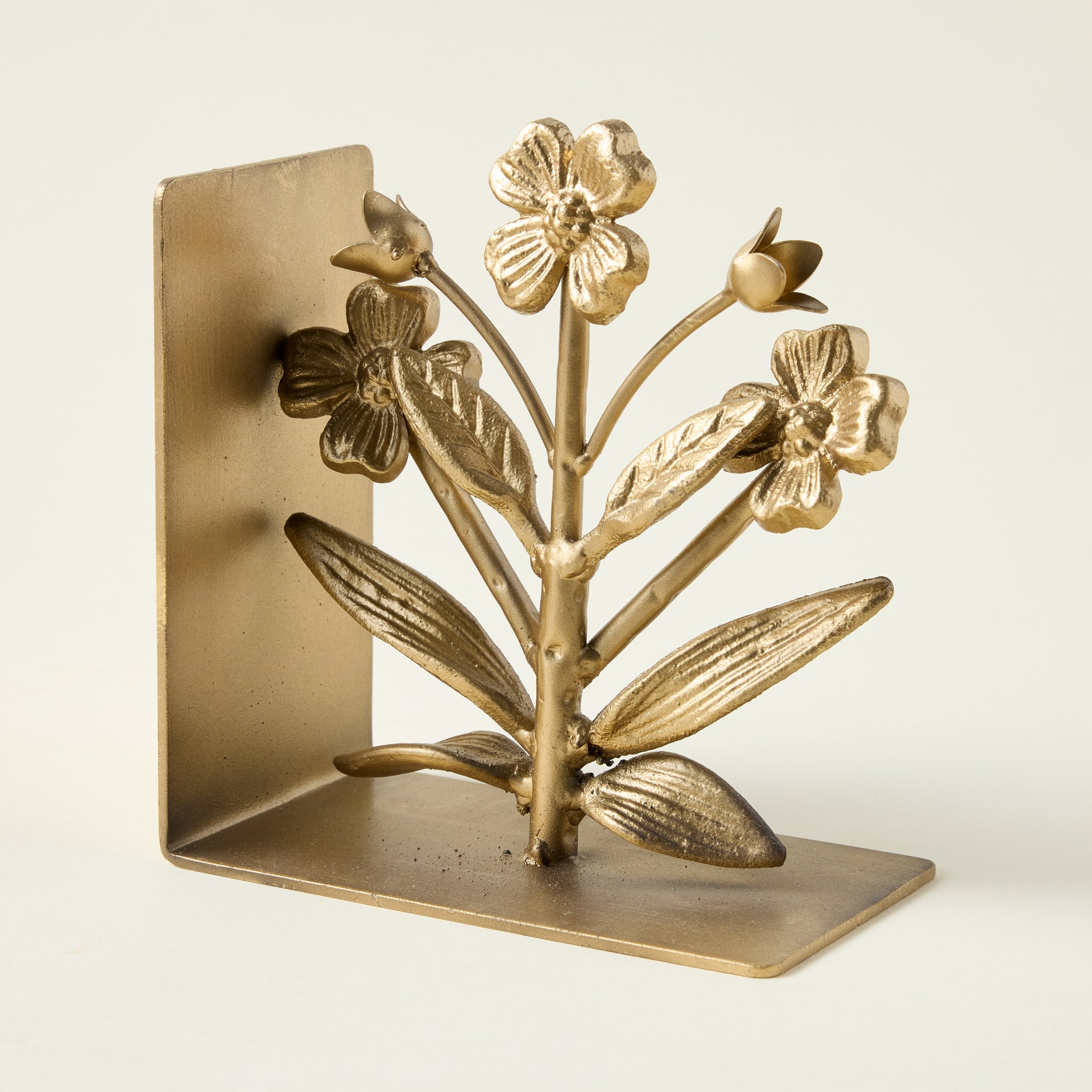 Cast iron flower-shaped bookends with a gold finish, styled to hold books on a shelf.