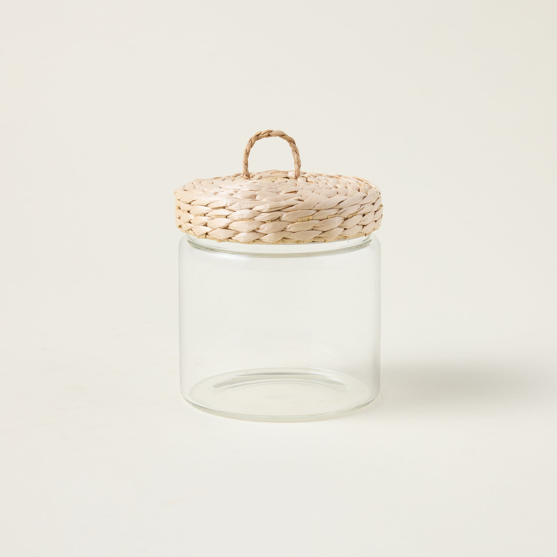 Glass storage jar with a handwoven lid made from natural grass, showcasing an organic and refined aesthetic.