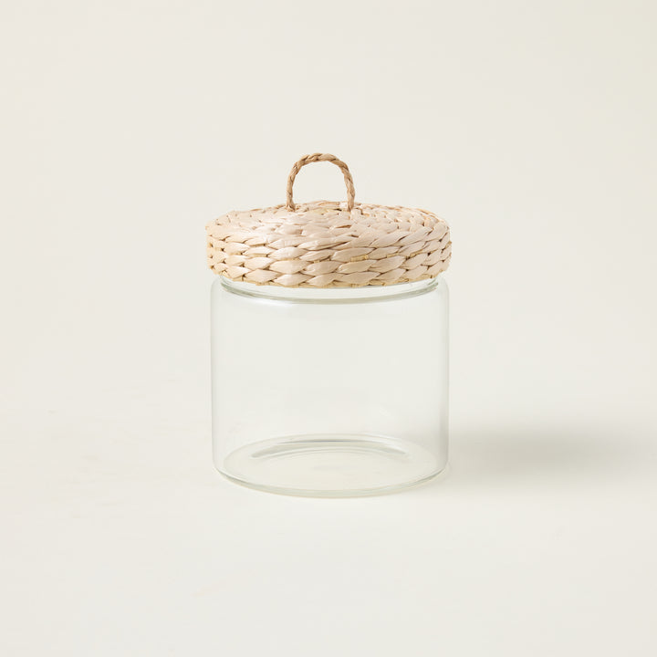 Glass storage jar with a handwoven lid made from natural grass, showcasing an organic and refined aesthetic.