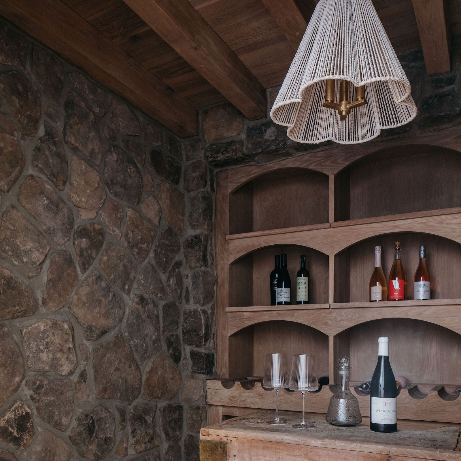 Wooden bar with wine bottles against a stone wall