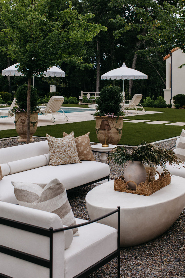 A white agate stone coffee table styled on a patio or deck with outdoor seating.