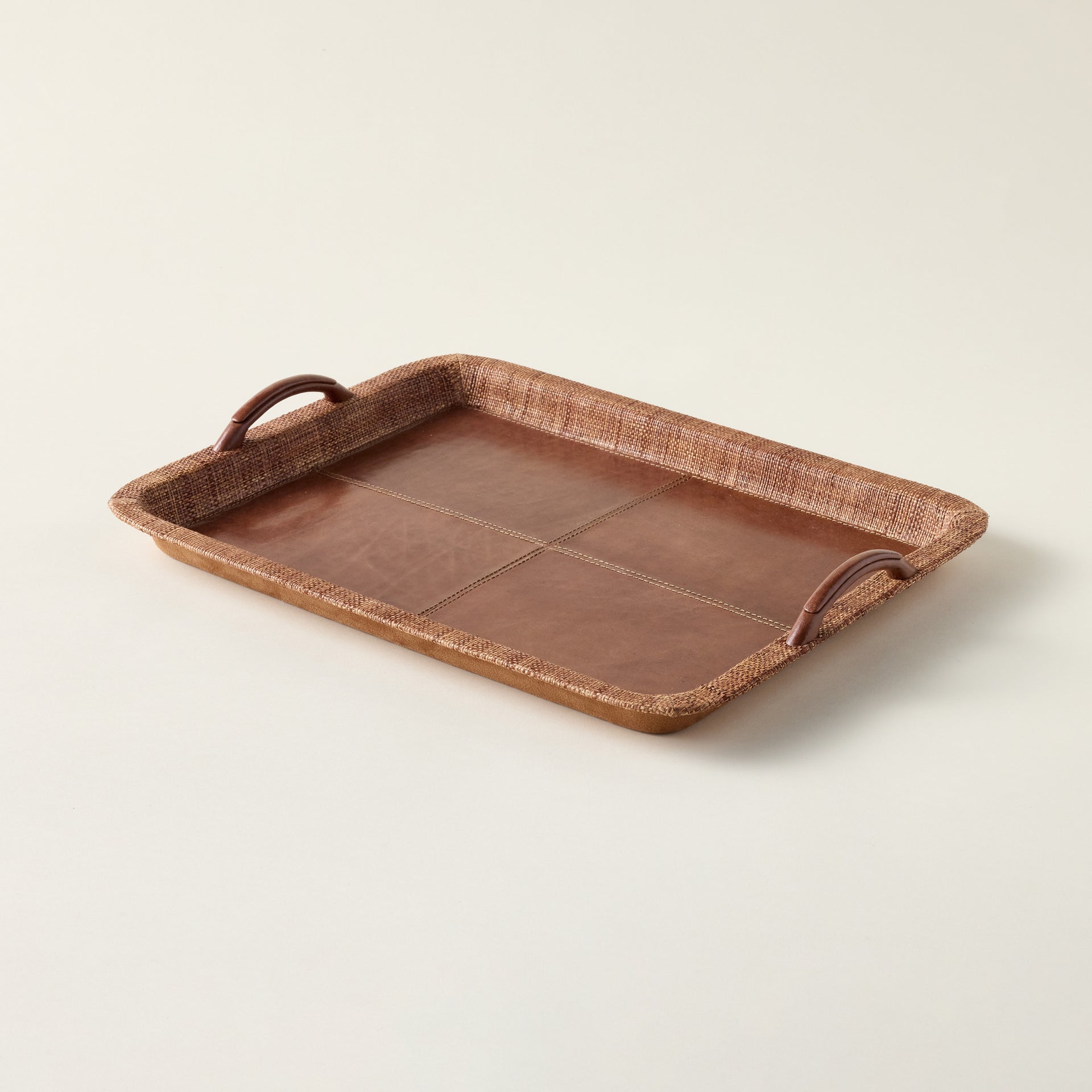 Handcrafted leather and raffia serving tray with a refined, organic texture.