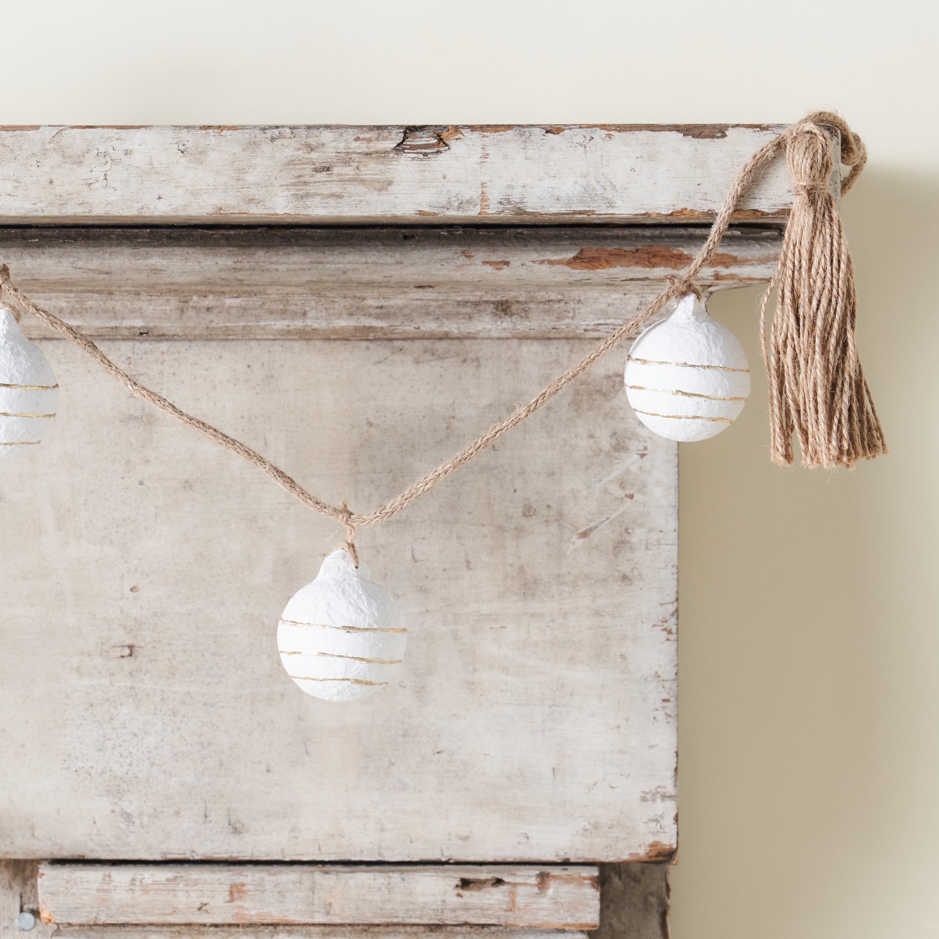 A decorative garland with paper mache balls, gold foil accents, and tassels.