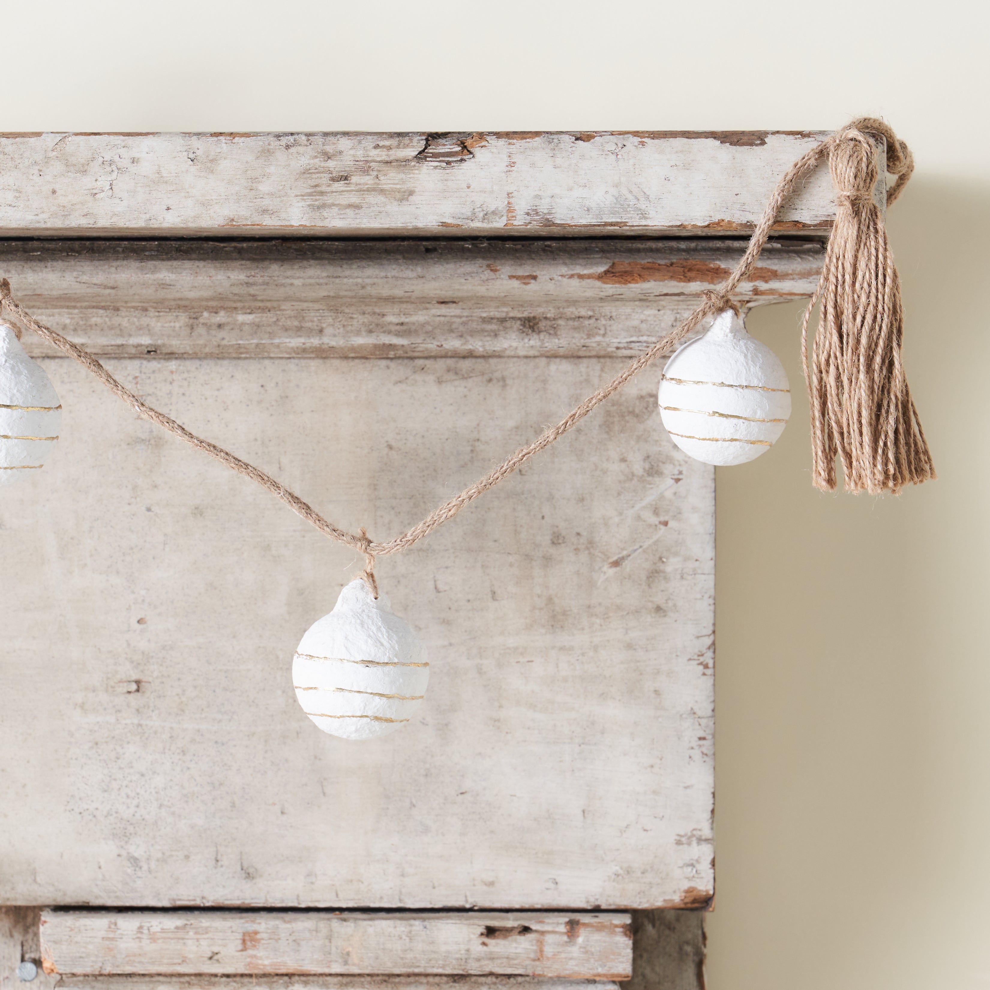 A decorative garland with paper mache balls, gold foil accents, and tassels.