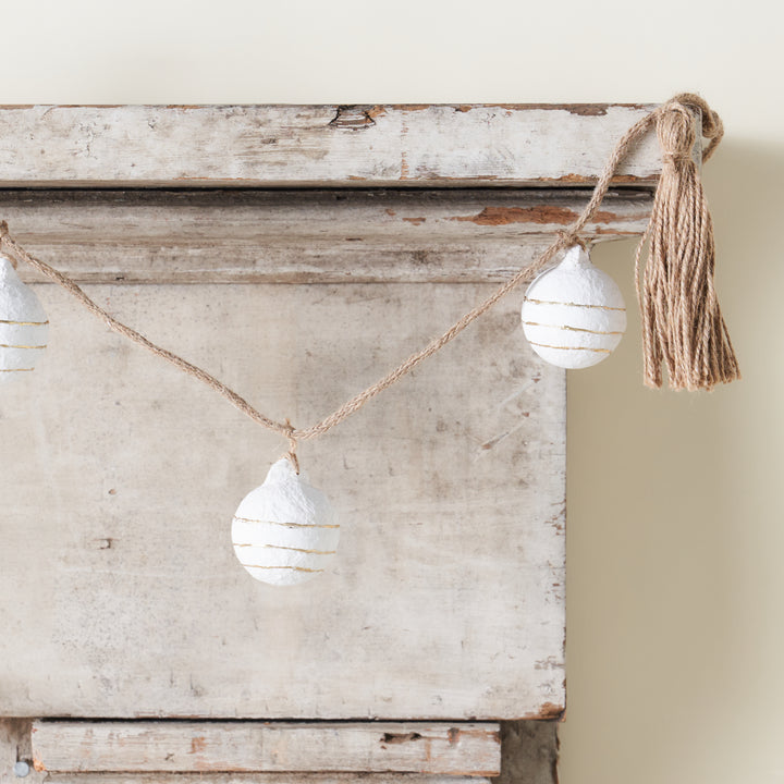 A decorative garland with paper mache balls, gold foil accents, and tassels.