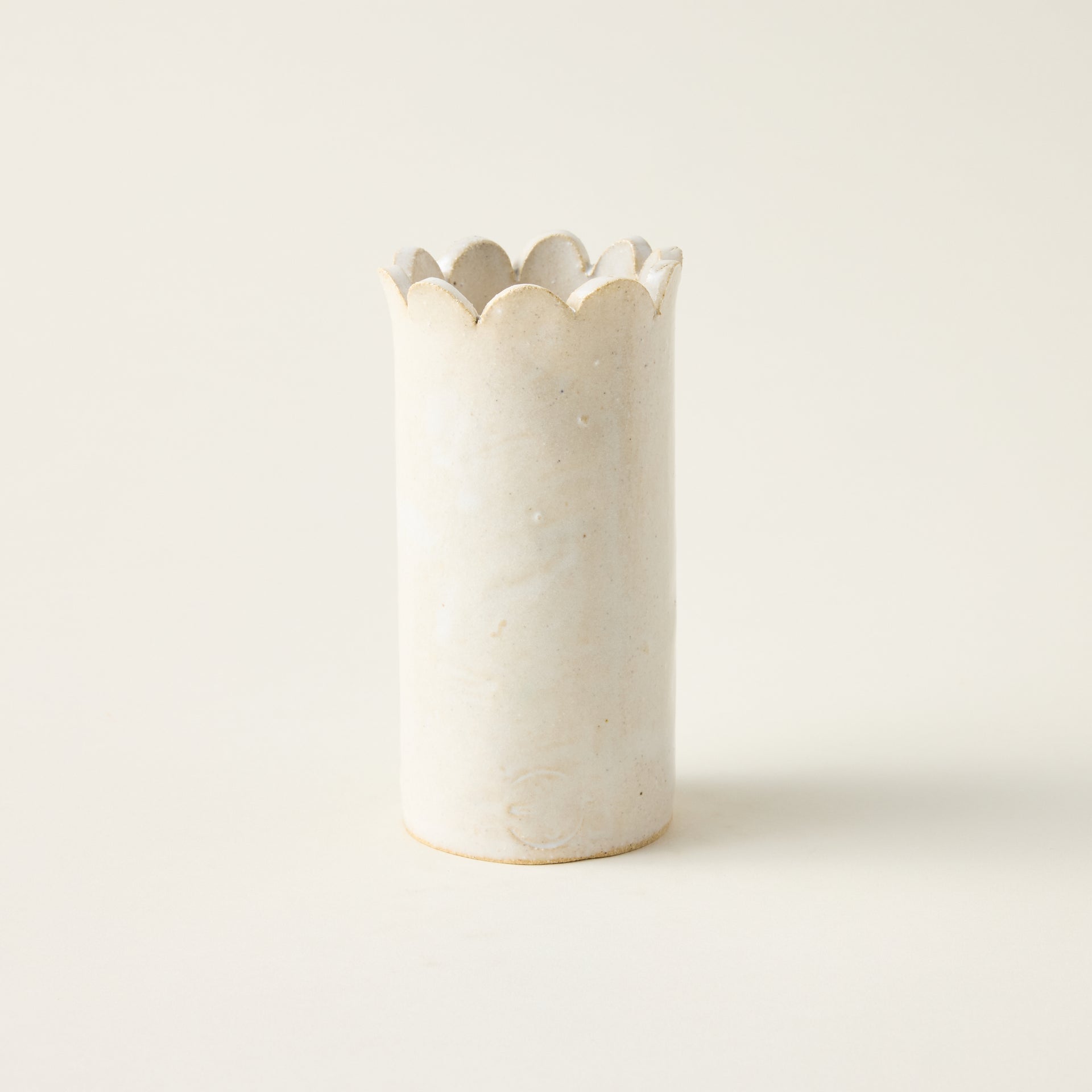 Handcrafted petite ceramic vase with a unique hand-cut scallop top and a minimalist cylindrical shape.