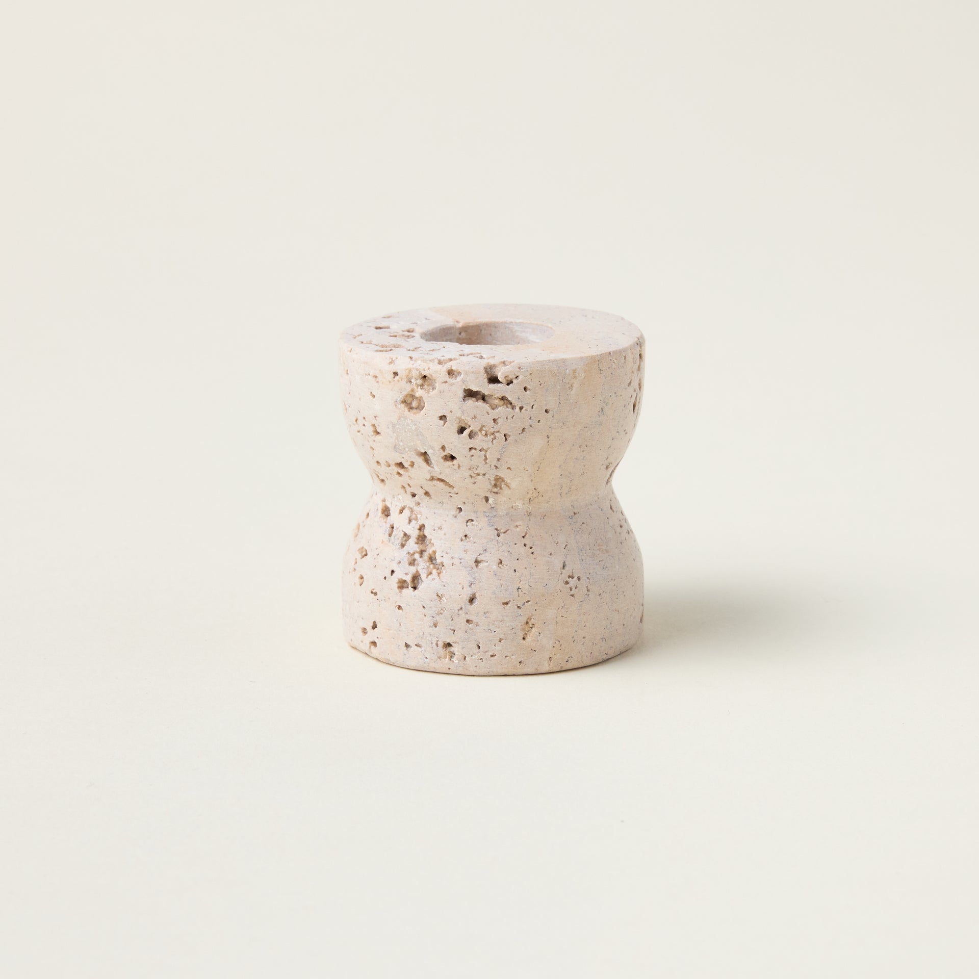 Sculptural taper candle holder crafted from genuine travertine marble with a smooth, refined finish.
