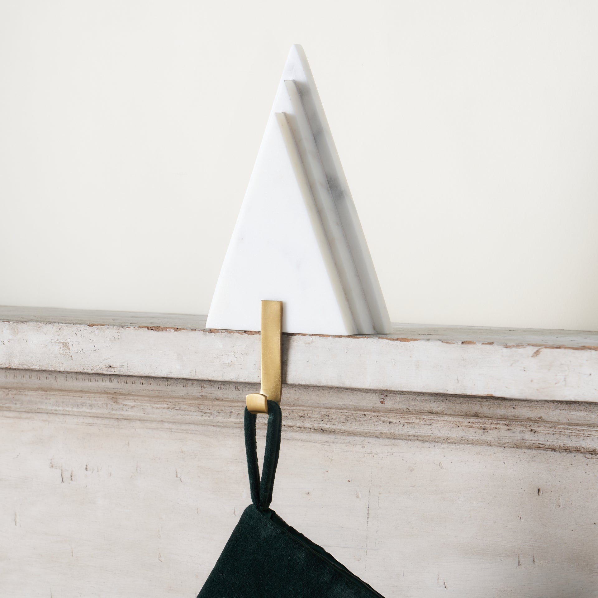 A decorative stocking holder with a white marble tree design and a gold metal hook.