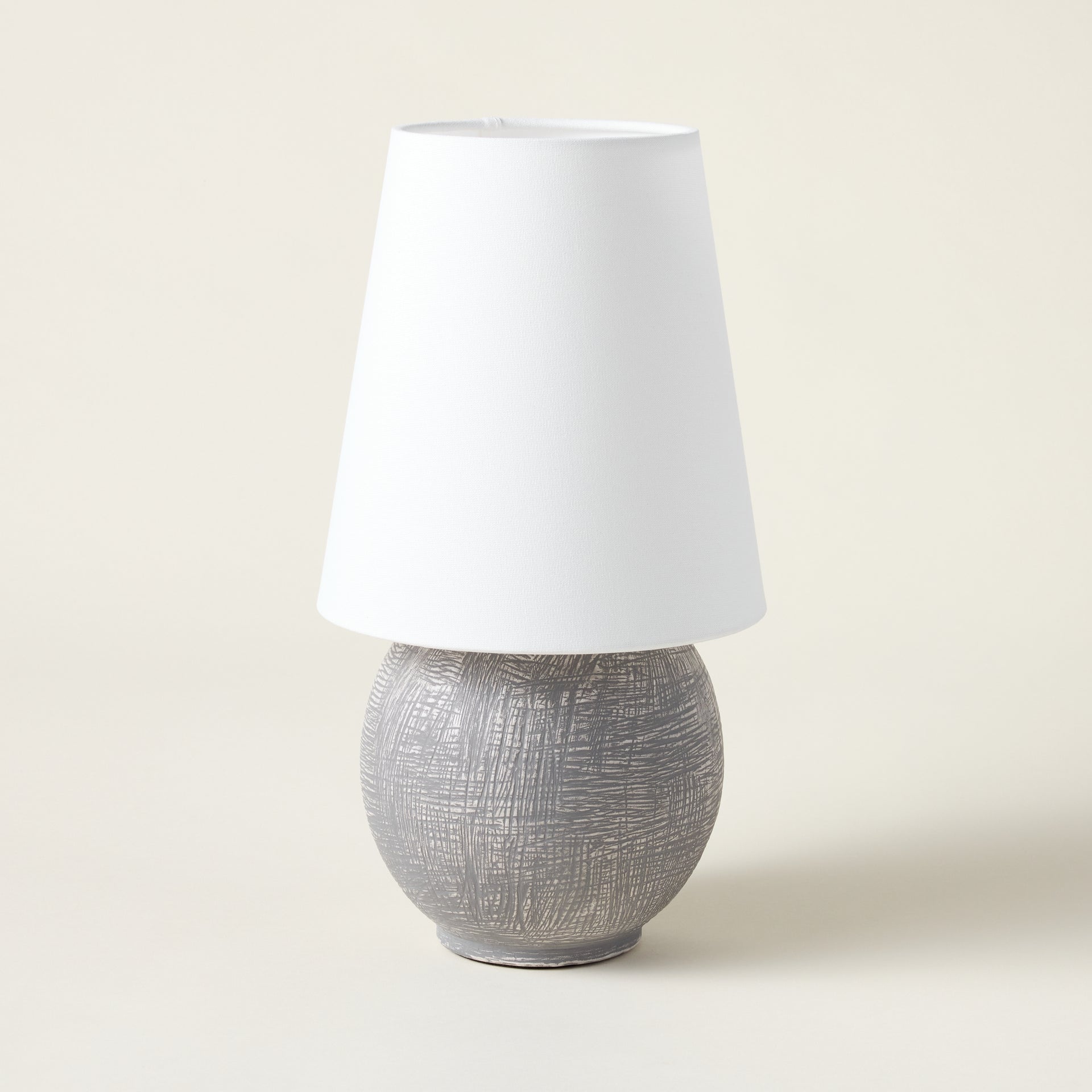 Sculptural rechargeable table lamp with a spherical ceramic base and an oversized linen shade.