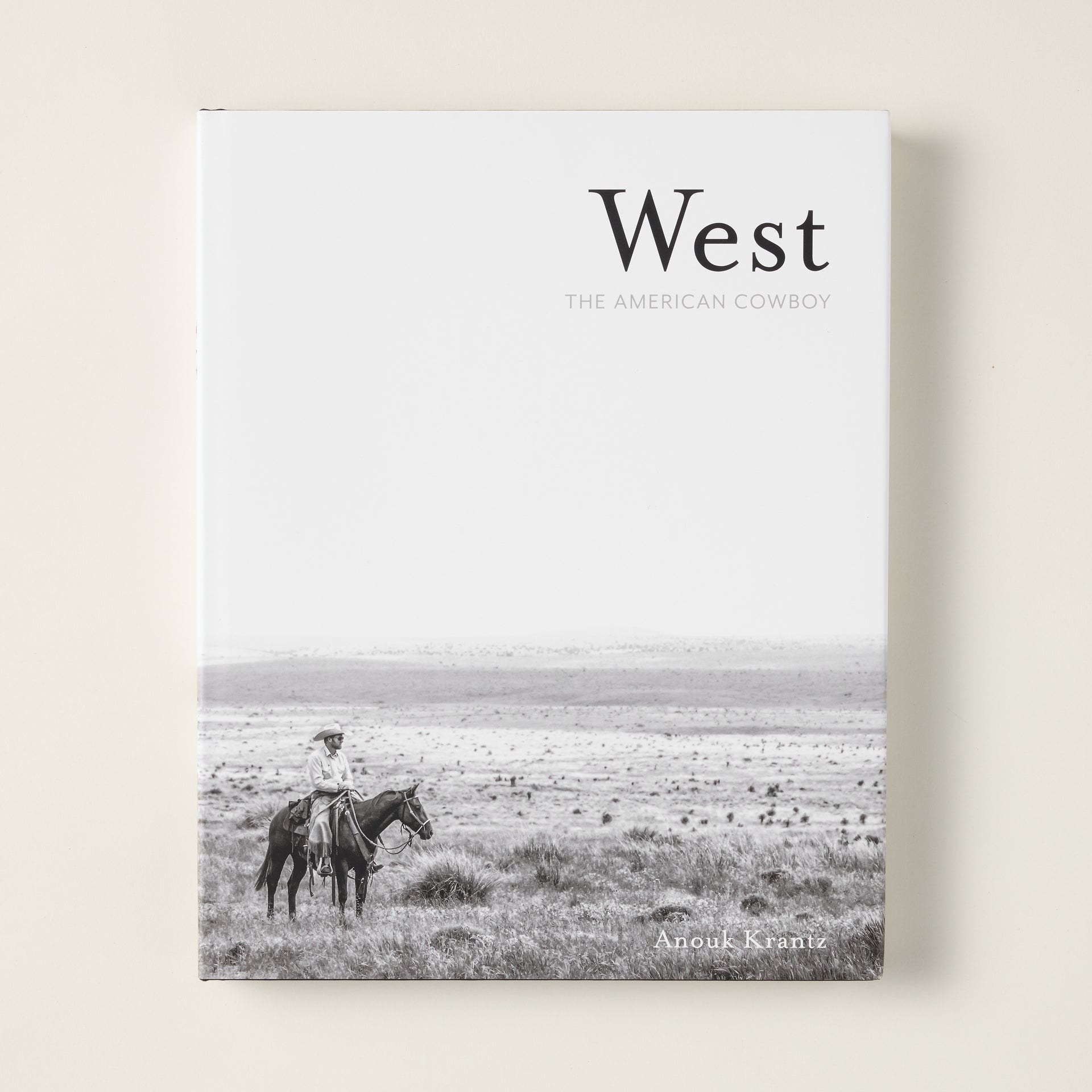 The cover of "West: The American Cowboy" book, featuring a stunning photograph of a cowboy in the American West.