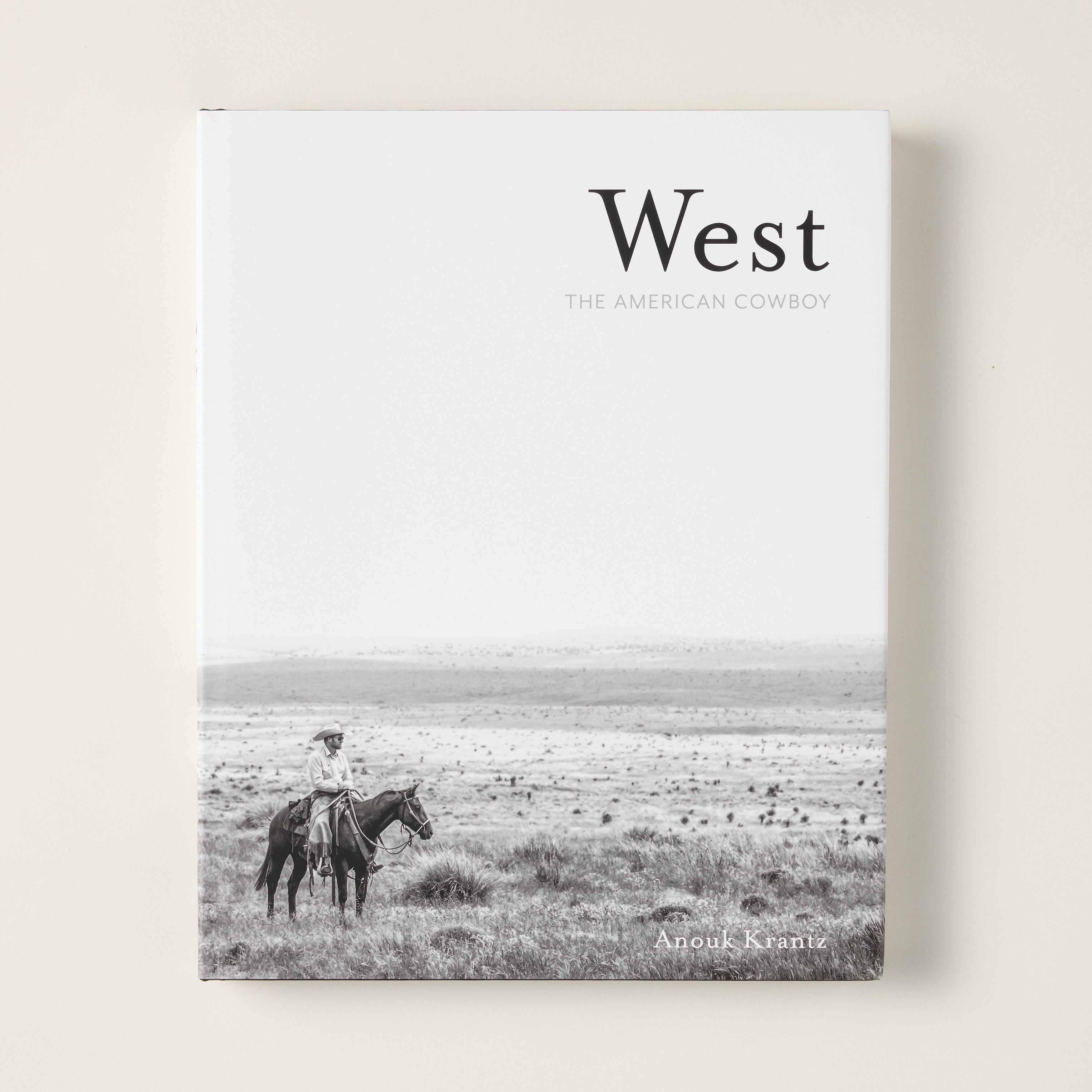 The cover of "West: The American Cowboy" book, featuring a stunning photograph of a cowboy in the American West.