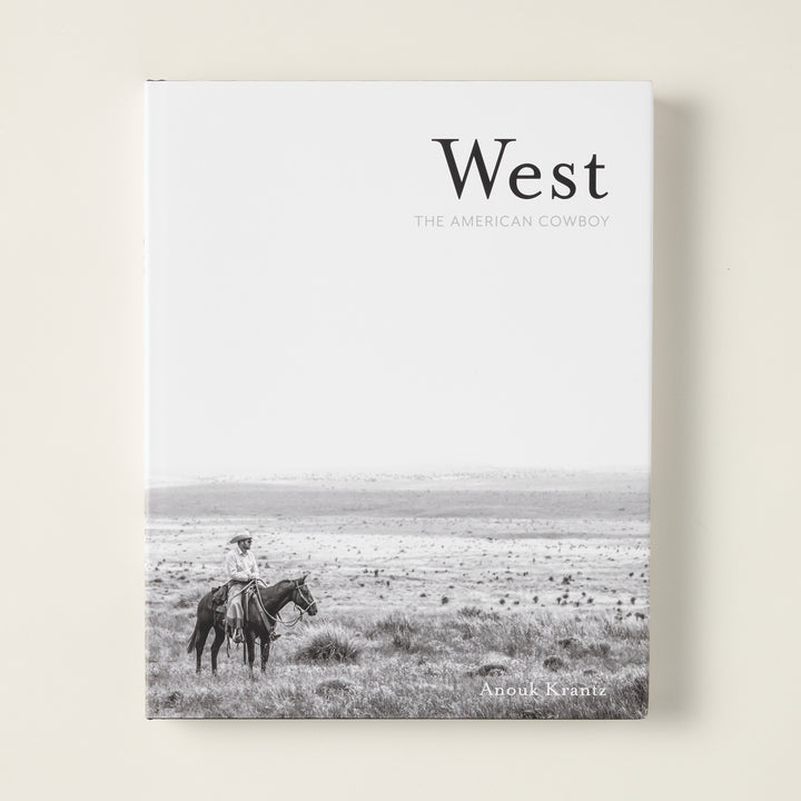 The cover of "West: The American Cowboy" book, featuring a stunning photograph of a cowboy in the American West.