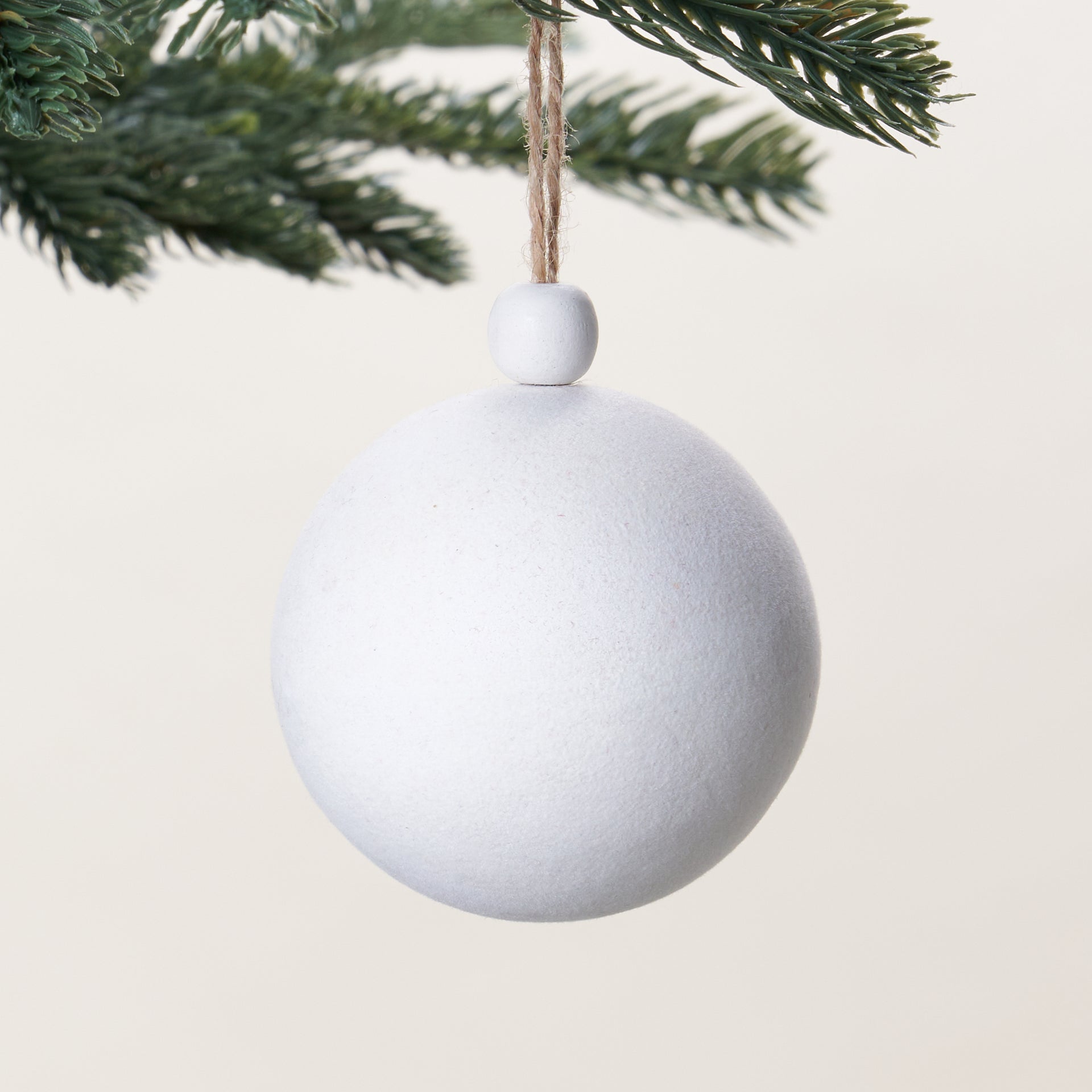 A decorative ornament with a white flocked finish and a wooden bead on top.