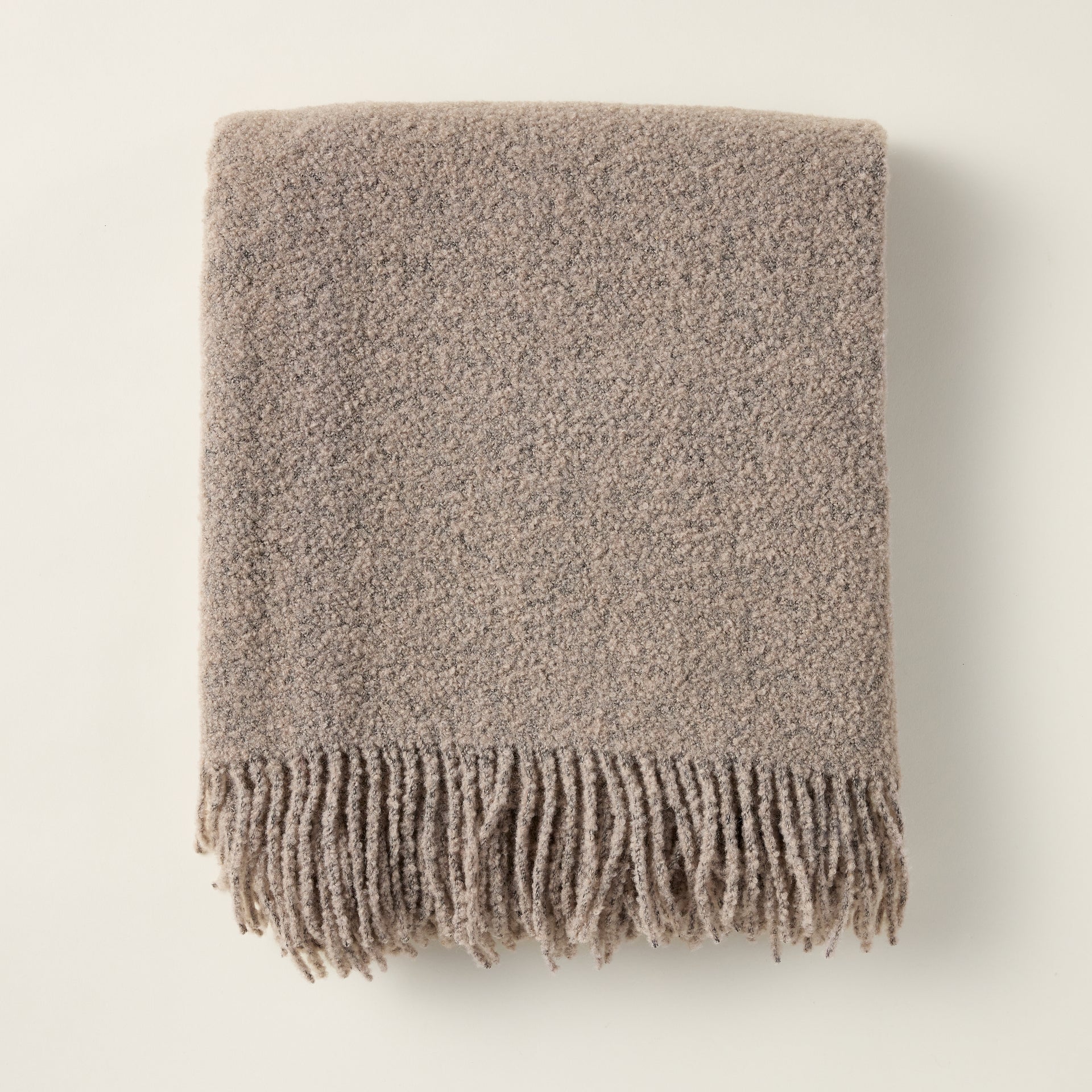 Wool boucle throw with a rich, textural weave, styled for a cozy and layered look.