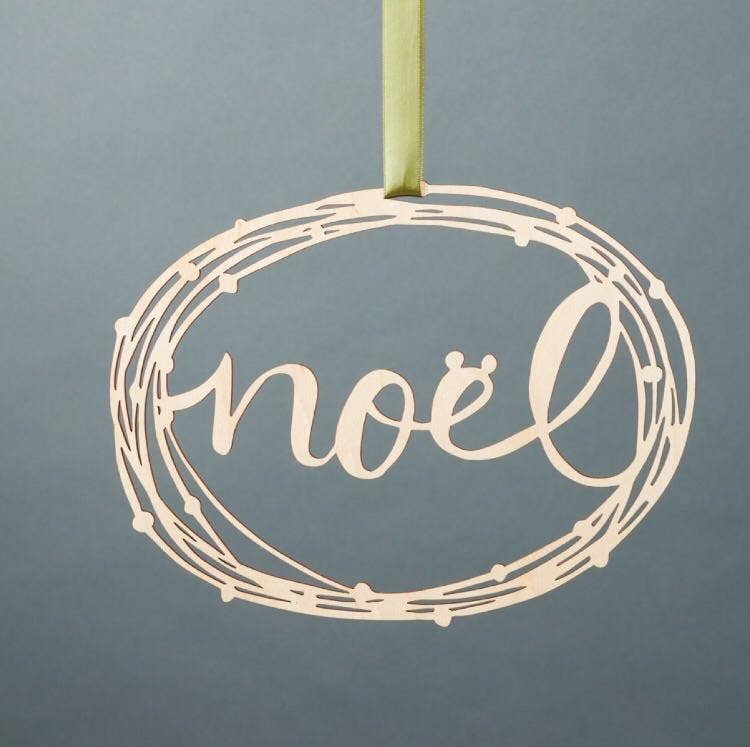 A decorative wreath with the word "Noel" on it, made from graceful birch branches.