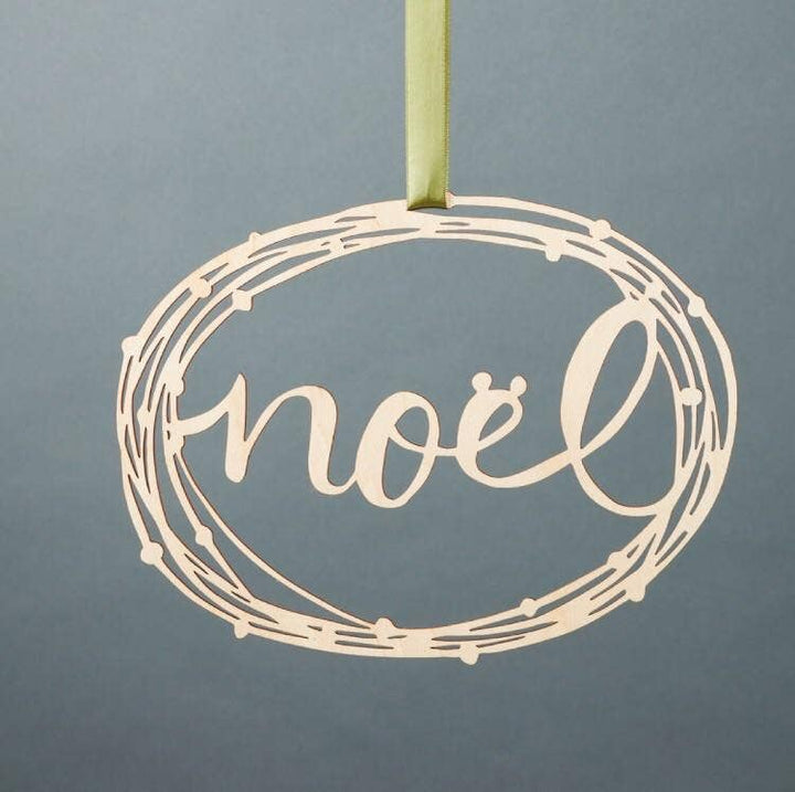 A decorative wreath with the word "Noel" on it, made from graceful birch branches.