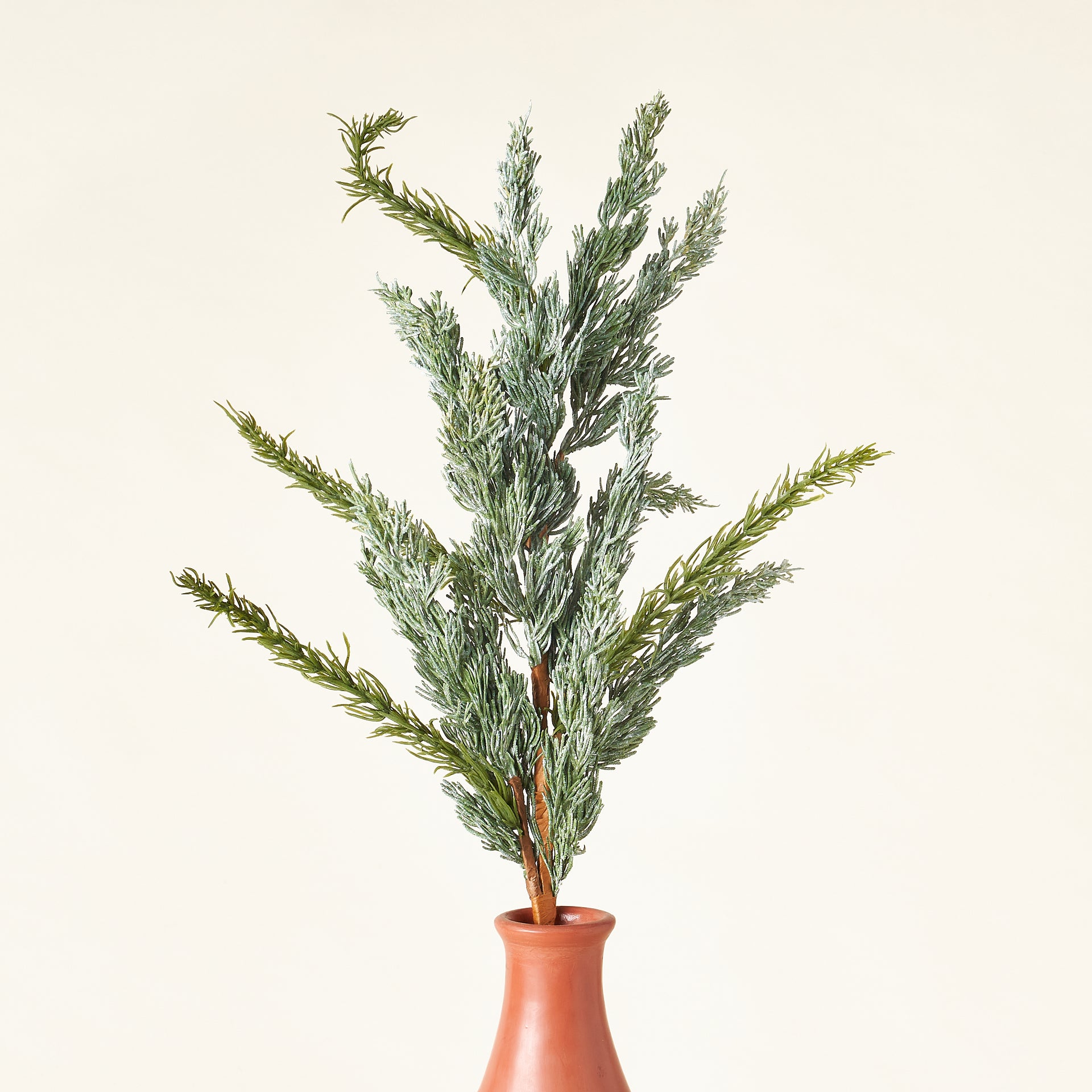 A faux cypress stem with realistic needles and a lifelike appearance.