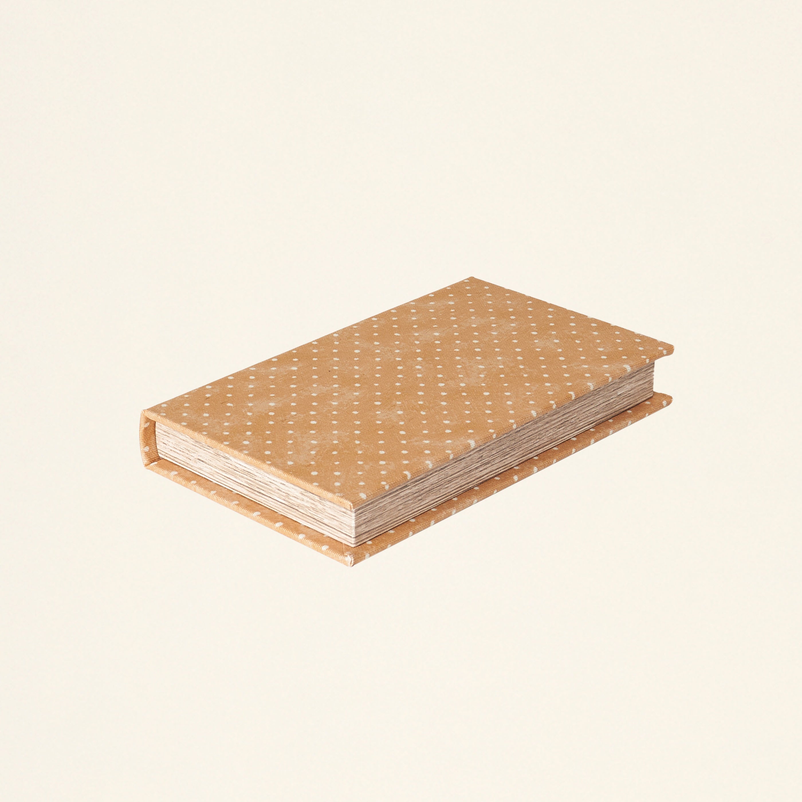 A decorative storage box shaped like a book, with an orange polka dot print.