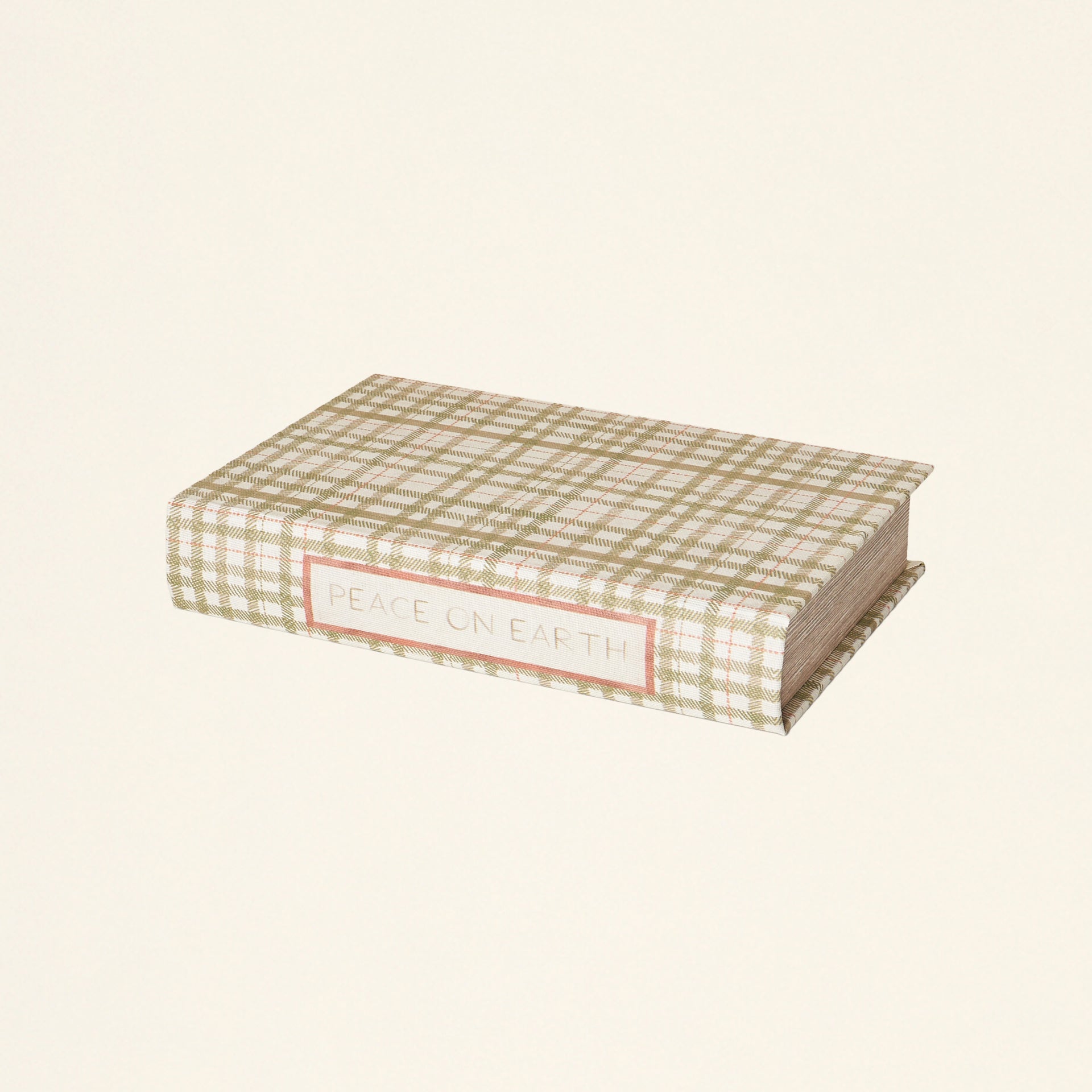 A decorative storage box shaped like a book, with a green plaid print and "Peace on Earth" written on the spine.