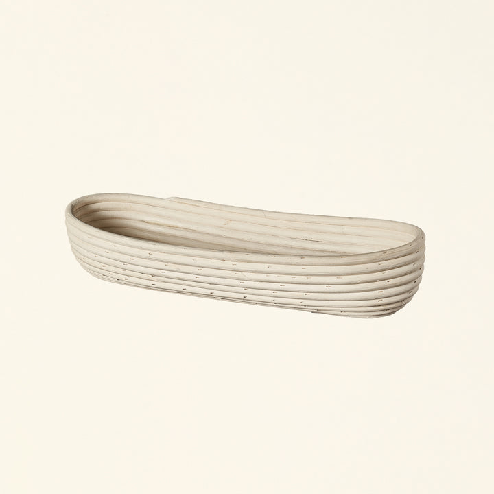 Natural rattan basket with a long, thin shape.