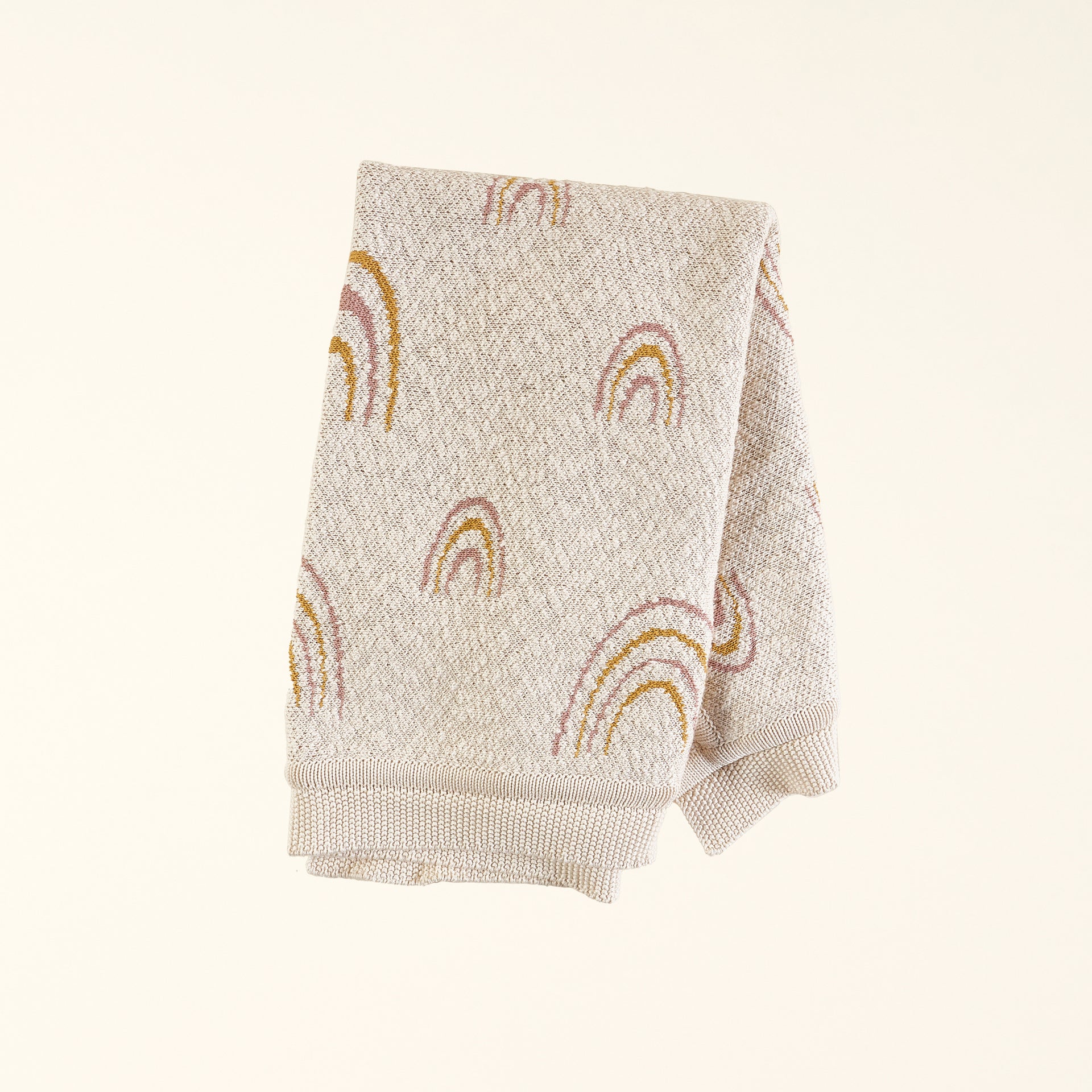 A soft, knit baby blanket with a neutral-colored rainbow pattern.