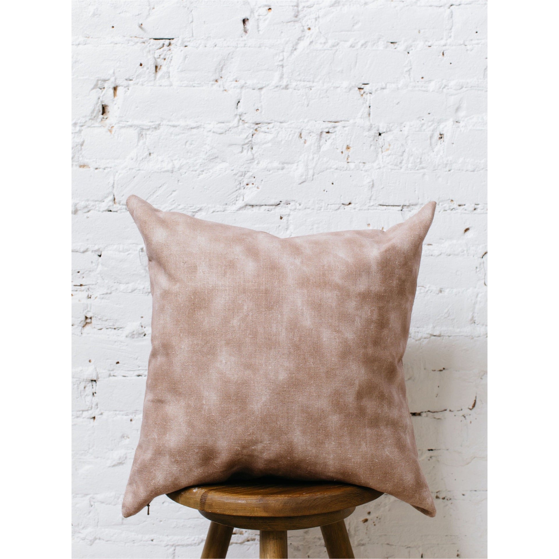 A double-sided, watercolor-patterned pillow cover with soft, blended colors, laid flat to show the full design on oatmeal linen fabric.
