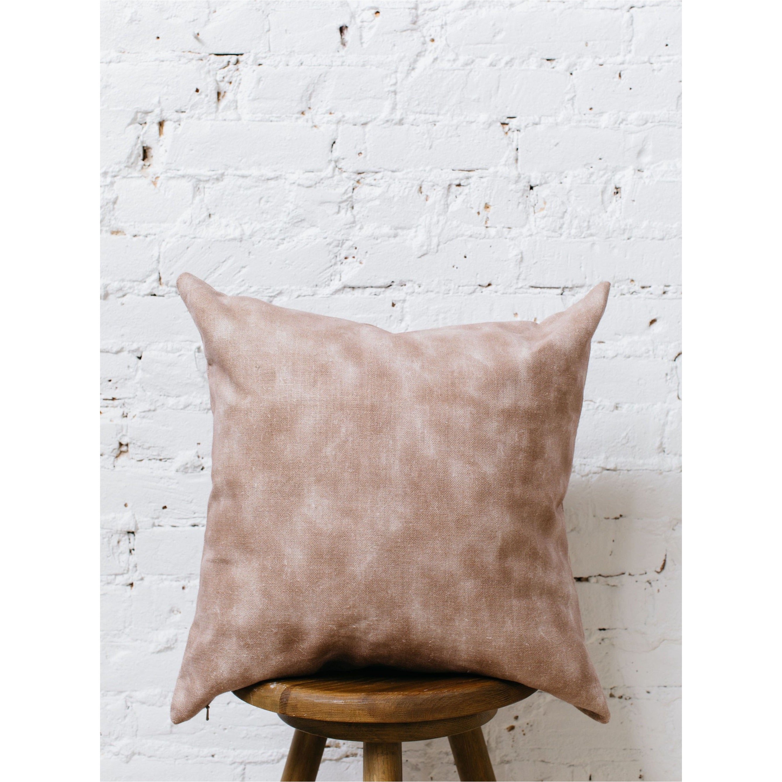 A double-sided, watercolor-patterned pillow cover with soft, blended colors, laid flat to show the full design on oatmeal linen fabric.