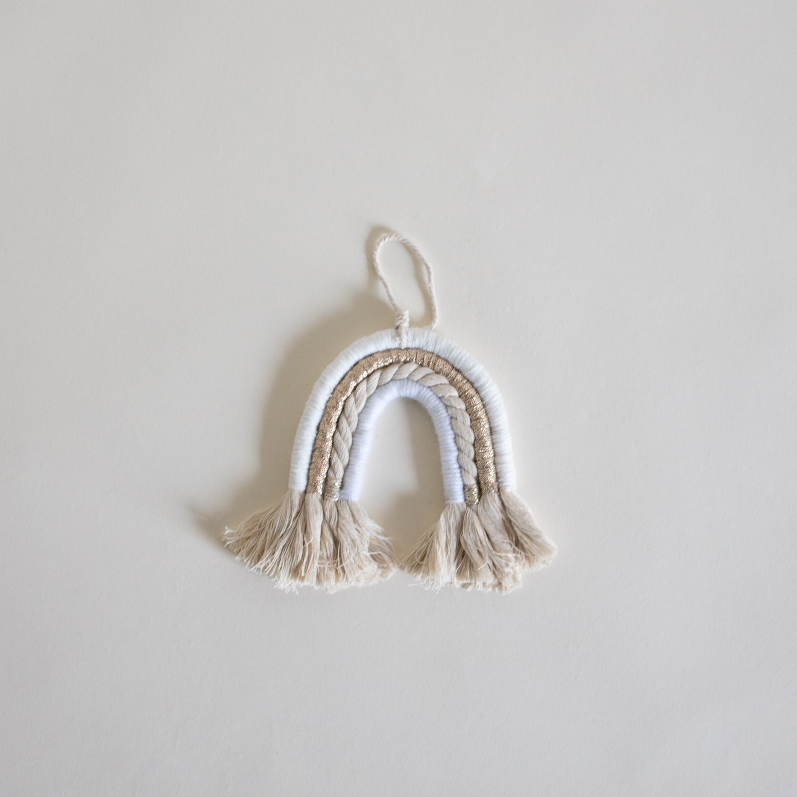 A decorative ornament in the shape of a rainbow, made from colorful rope.